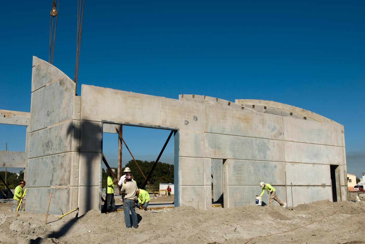 CAPE CANAVERAL, Fla. - In Launch Complex 39 at NASA's Kennedy Space Center in Florida, steady progress is made by a team of construction workers to erect the walls of the Propellants North Administrative and Maintenance Facility.    A tilt-up construction method is being used to erect a THERMOMASS concrete wall insulation system for the facility's walls.  In this approach, the exterior layer of concrete for the wall panels is poured and leveled on the building's footprint. Then, prefabricated, predrilled insulation sheets are arranged on top of the unhardened concrete, and connectors, designed to hold the sandwiched layers of concrete and insulation secure, are inserted through the predrilled holes. Next, the structural wythe is poured.  Once cured, these panels are lifted upright to form the building's envelope.  The facility will have a two-story administrative building to house managers, mechanics and technicians who fuel spacecraft at Kennedy adjacent to an 1,800-square-foot single-story shop to store cryogenic fuel transfer equipment.  The new facility will feature high-efficiency roofs and walls, “Cool Dry Quiet” air conditioning with energy recovery technology, efficient lighting, and other sustainable features. The facility is striving to qualify for the U.S. Green Building Council’s Leadership in Energy and Environmental Design, or LEED, Platinum certification. If successful, Propellants North will be the first Kennedy facility to achieve this highest of LEED ratings after it is completed in the summer of 2010.  The facility was designed for NASA by Jones Edmunds and Associates.  Photo credit: NASA/Jim Grossmann