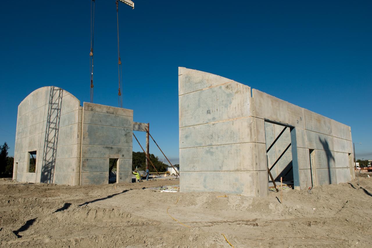 CAPE CANAVERAL, Fla. - In Launch Complex 39 at NASA's Kennedy Space Center in Florida, reminiscent of a barn-raising, the Propellants North Administrative and Maintenance Facility springs into being in a single day as its walls are lifted into position.    A tilt-up construction method is being used to erect a THERMOMASS concrete wall insulation system for the facility's walls.  In this approach, the exterior layer of concrete for the wall panels is poured and leveled on the building's footprint. Then, prefabricated, predrilled insulation sheets are arranged on top of the unhardened concrete, and connectors, designed to hold the sandwiched layers of concrete and insulation secure, are inserted through the predrilled holes. Next, the structural wythe is poured.  Once cured, these panels are lifted upright to form the building's envelope.  The facility will have a two-story administrative building to house managers, mechanics and technicians who fuel spacecraft at Kennedy adjacent to an 1,800-square-foot single-story shop to store cryogenic fuel transfer equipment.  The new facility will feature high-efficiency roofs and walls, “Cool Dry Quiet” air conditioning with energy recovery technology, efficient lighting, and other sustainable features. The facility is striving to qualify for the U.S. Green Building Council’s Leadership in Energy and Environmental Design, or LEED, Platinum certification. If successful, Propellants North will be the first Kennedy facility to achieve this highest of LEED ratings after it is completed in the summer of 2010.  The facility was designed for NASA by Jones Edmunds and Associates.  Photo credit: NASA/Jim Grossmann