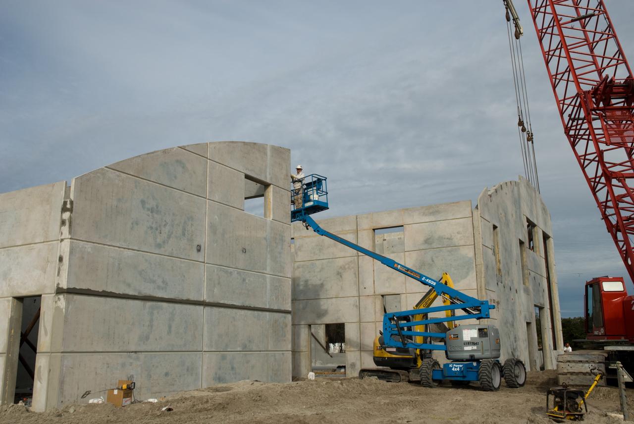 CAPE CANAVERAL, Fla. - In Launch Complex 39 at NASA's Kennedy Space Center in Florida, the last outside wall of the Propellants North Administrative and Maintenance Facility is lifted into place.    Concrete layers on either side of high-density foam insulation in the facility's walls will prevent any transfer of radiant heat between the exterior and interior of the buildings.  A tilt-up construction method is being used to erect a THERMOMASS concrete wall insulation system for the facility's walls.  In this approach, the exterior layer of concrete for the wall panels is poured and leveled on the building's footprint. Then, prefabricated, predrilled insulation sheets are arranged on top of the unhardened concrete, and connectors, designed to hold the sandwiched layers of concrete and insulation secure, are inserted through the predrilled holes. Next, the structural wythe is poured.  Once cured, these panels are lifted upright to form the building's envelope.  The facility will have a two-story administrative building to house managers, mechanics and technicians who fuel spacecraft at Kennedy adjacent to an 1,800-square-foot single-story shop to store cryogenic fuel transfer equipment.  The new facility will feature high-efficiency roofs and walls, “Cool Dry Quiet” air conditioning with energy recovery technology, efficient lighting, and other sustainable features. The facility is striving to qualify for the U.S. Green Building Council’s Leadership in Energy and Environmental Design, or LEED, Platinum certification. If successful, Propellants North will be the first Kennedy facility to achieve this highest of LEED ratings after it is completed in the summer of 2010.  The facility was designed for NASA by Jones Edmunds and Associates.  Photo credit: NASA/Jim Grossmann
