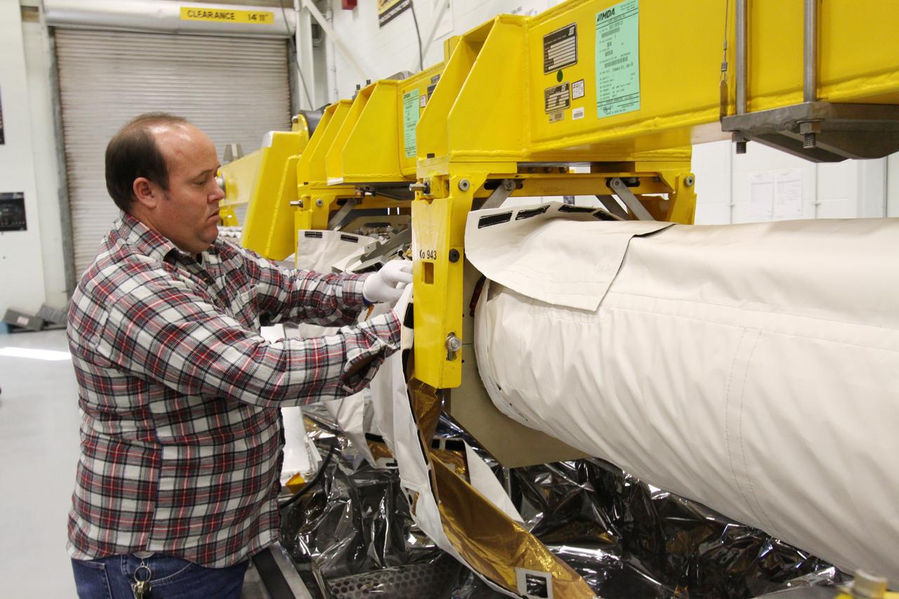 CAPE CANAVERAL, Fla. - In the Remote Manipulator System Lab inside the Vehicle Assembly Building at NASA's Kennedy Space Center in Florida, Patrick Manning, an advanced systems technician with United Space Alliance, installs the mid-transition thermal blanket onto the inspection boom assembly, or IBA, on space shuttle Atlantis' orbiter boom sensor system, or OBSS.  The IBA is removed from the shuttle every other processing flow for a detailed inspection. After five consecutive flights, all IBA internal components are submitted to a thorough electrical checkout in the lab.    The 50-foot-long OBSS attaches to the end of the shuttle’s robotic arm and supports the cameras and laser systems used to inspect the shuttle’s thermal protection system while in space.  Atlantis is next slated to deliver an Integrated Cargo Carrier and Russian-built Mini Research Module to the International Space Station on the STS-132 mission. The second in a series of new pressurized components for Russia, the module will be permanently attached to the Zarya module. Three spacewalks are planned to store spare components outside the station, including six spare batteries, a boom assembly for the Ku-band antenna and spares for the Canadian Dextre robotic arm extension. A radiator, airlock and European robotic arm for the Russian Multi-purpose Laboratory Module also are payloads on the flight.  Launch is targeted for May 14, 2010.  Photo credit: NASA/Jack Pfaller