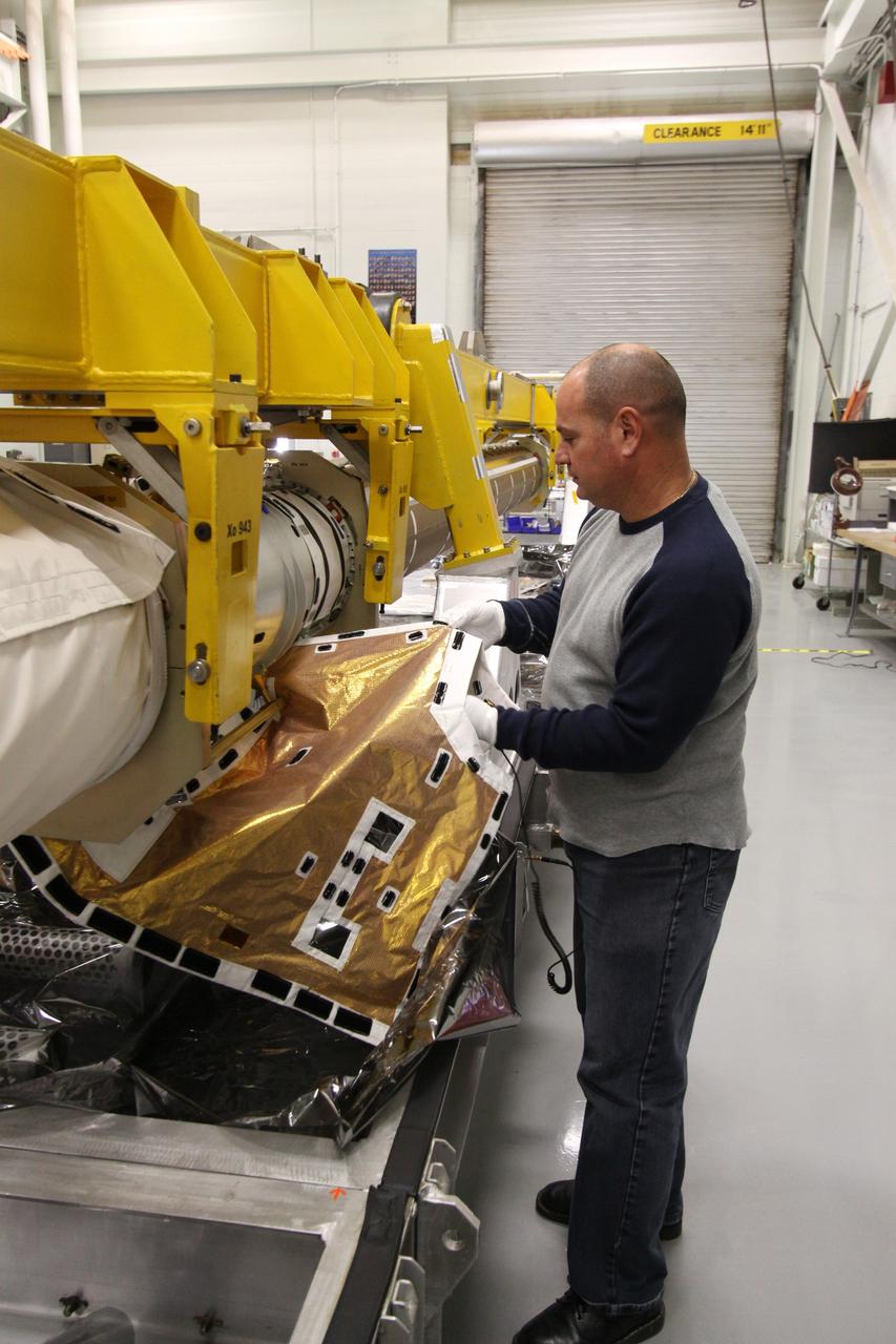 CAPE CANAVERAL, Fla. - In the Remote Manipulator System Lab, or RMS Lab, inside the Vehicle Assembly Building at NASA's Kennedy Space Center in Florida, Rafael Rodriguez, lead RMS advanced systems technician with United Space Alliance, installs the mid-transition thermal blanket onto the inspection boom assembly, or IBA, on space shuttle Atlantis' orbiter boom sensor system, or OBSS.  The IBA is removed from the shuttle every other processing flow for a detailed inspection. After five consecutive flights, all IBA internal components are submitted to a thorough electrical checkout in the lab.    The 50-foot-long OBSS attaches to the end of the shuttle’s robotic arm and supports the cameras and laser systems used to inspect the shuttle’s thermal protection system while in space.  Atlantis is next slated to deliver an Integrated Cargo Carrier and Russian-built Mini Research Module to the International Space Station on the STS-132 mission. The second in a series of new pressurized components for Russia, the module will be permanently attached to the Zarya module. Three spacewalks are planned to store spare components outside the station, including six spare batteries, a boom assembly for the Ku-band antenna and spares for the Canadian Dextre robotic arm extension. A radiator, airlock and European robotic arm for the Russian Multi-purpose Laboratory Module also are payloads on the flight.  Launch is targeted for May 14, 2010.  Photo credit: NASA/Jack Pfaller
