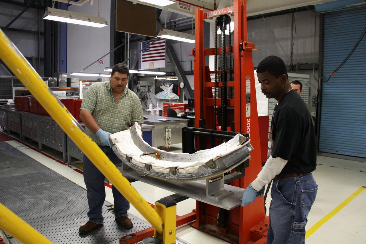 CAPE CANAVERAL, Fla. - In Orbiter Processing Facility 1 at NASA's Kennedy Space Center in Florida, United Space Alliance technicians prepare to install the chin panel on space shuttle Atlantis.    The chin panel is a semicircular-shaped section of reinforced carbon-carbon that fits under the shuttle's nose cap and is part of its thermal protection system.  Atlantis is next slated to deliver an Integrated Cargo Carrier and Russian-built Mini Research Module to the International Space Station on the STS-132 mission. The second in a series of new pressurized components for Russia, the module will be permanently attached to the Zarya module. Three spacewalks are planned to store spare components outside the station, including six spare batteries, a boom assembly for the Ku-band antenna and spares for the Canadian Dextre robotic arm extension. A radiator, airlock and European robotic arm for the Russian Multi-purpose Laboratory Module also are payloads on the flight.  Launch is targeted for May 14, 2010.    Photo credit: NASA/Ben Smegelsky