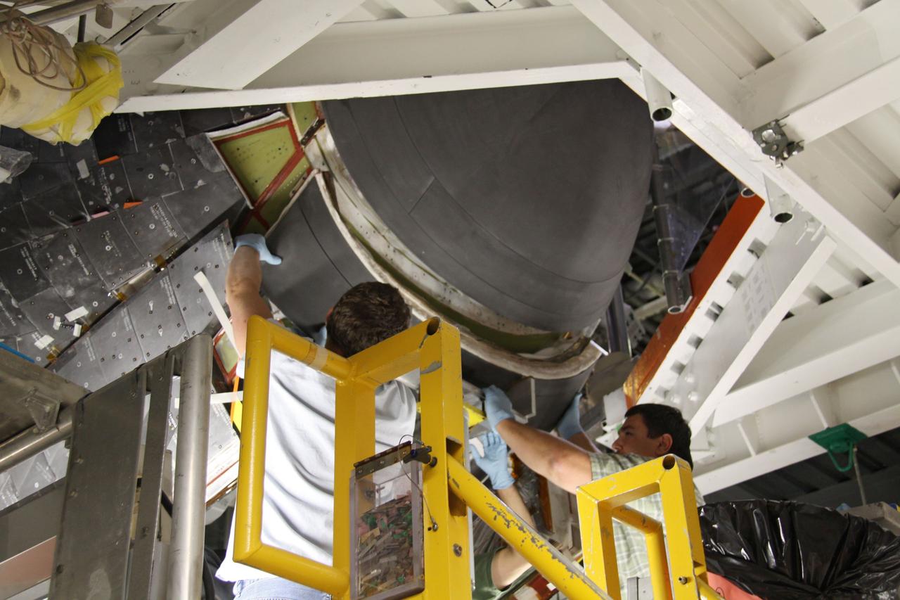 CAPE CANAVERAL, Fla. - In Orbiter Processing Facility 1 at NASA's Kennedy Space Center in Florida, United Space Alliance technicians position the chin panel on space shuttle Atlantis for installation.    The chin panel is a semicircular-shaped section of reinforced carbon-carbon that fits under the shuttle's nose cap and is part of its thermal protection system.  Atlantis is next slated to deliver an Integrated Cargo Carrier and Russian-built Mini Research Module to the International Space Station on the STS-132 mission. The second in a series of new pressurized components for Russia, the module will be permanently attached to the Zarya module. Three spacewalks are planned to store spare components outside the station, including six spare batteries, a boom assembly for the Ku-band antenna and spares for the Canadian Dextre robotic arm extension. A radiator, airlock and European robotic arm for the Russian Multi-purpose Laboratory Module also are payloads on the flight.  Launch is targeted for May 14, 2010.    Photo credit: NASA/Ben Smegelsky