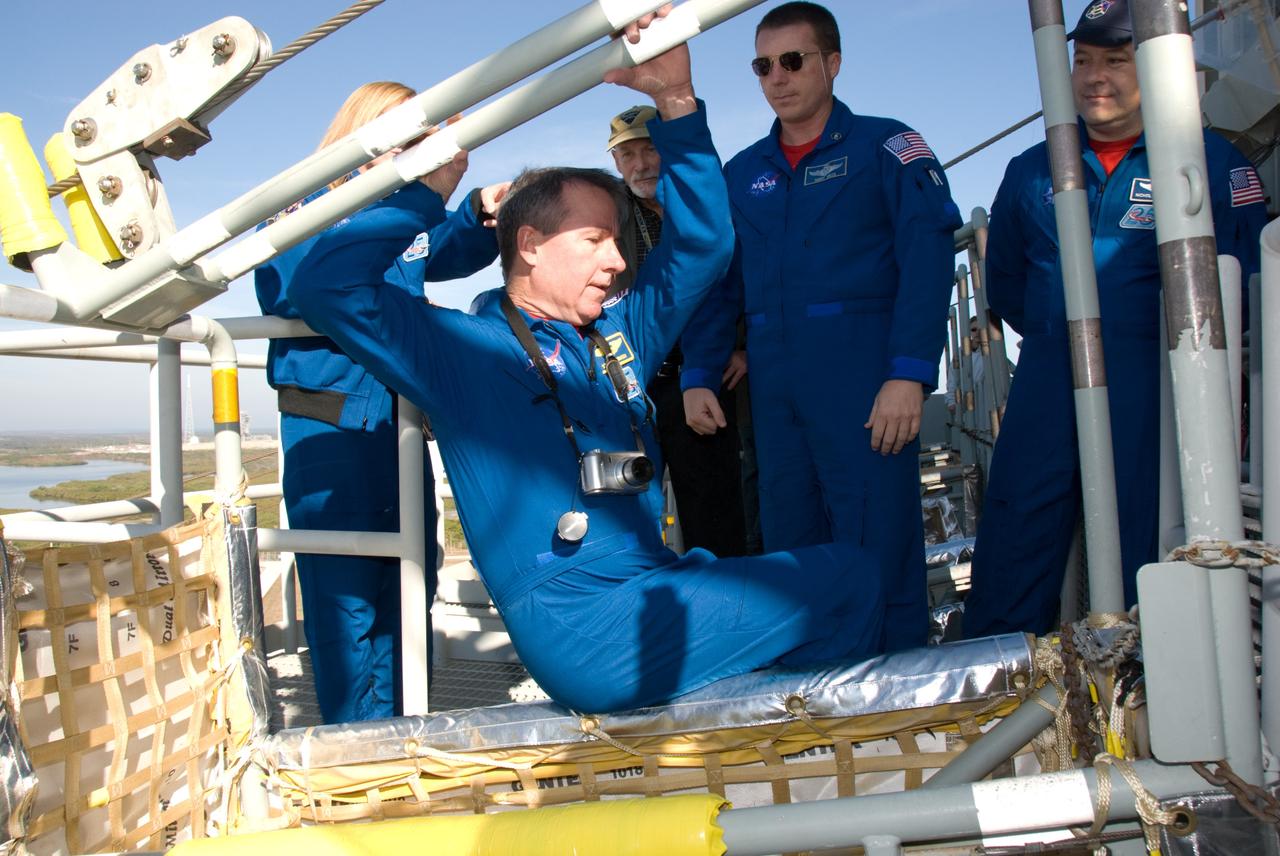 CAPE CANAVERAL, Fla. - On Launch Pad 39A at NASA's Kennedy Space Center in Florida, STS-130 Mission Specialist Stephen Robinson hoists himself into a slidewire basket during training on the emergency exit system at the pad. The system includes seven baskets suspended from seven slidewires that extend from the fixed service structure to a landing zone 1,200 feet west of the pad. The crew members of space shuttle Endeavour's upcoming mission are at Kennedy for training related to their launch dress rehearsal, the Terminal Countdown Demonstration Test. The primary payload on STS-130 is the International Space Station's Node 3, Tranquility, a pressurized module that will provide room for many of the station's life support systems. Attached to one end of Tranquility is a cupola, a unique work area with six windows on its sides and one on top. Endeavour's launch is targeted for Feb. 7. For information on the STS-130 mission and crew, visit http://www.nasa.gov/mission_pages/shuttle/shuttlemissions/sts130/index.html. Photo credit: NASA/Kim Shiflett