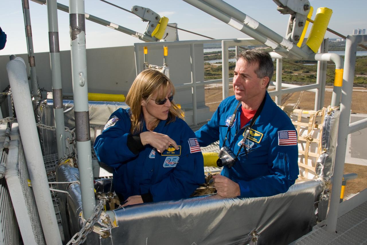 CAPE CANAVERAL, Fla. - On Launch Pad 39A at NASA's Kennedy Space Center in Florida, STS-130 Mission Specialists Kathryn Hire and Stephen Robinson experience a slidewire basket first hand during training on the emergency exit system at the pad. The system includes seven baskets suspended from seven slidewires that extend from the fixed service structure to a landing zone 1,200 feet west of the pad. The crew members of space shuttle Endeavour's upcoming mission are at Kennedy for training related to their launch dress rehearsal, the Terminal Countdown Demonstration Test. The primary payload on STS-130 is the International Space Station's Node 3, Tranquility, a pressurized module that will provide room for many of the station's life support systems. Attached to one end of Tranquility is a cupola, a unique work area with six windows on its sides and one on top. Endeavour's launch is targeted for Feb. 7. For information on the STS-130 mission and crew, visit http://www.nasa.gov/mission_pages/shuttle/shuttlemissions/sts130/index.html. Photo credit: NASA/Kim Shiflett