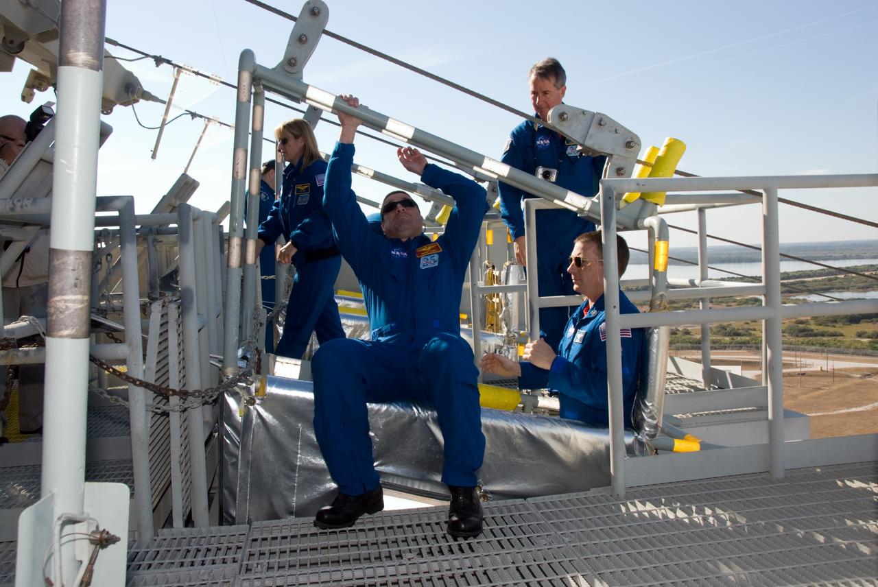 CAPE CANAVERAL, Fla. - On Launch Pad 39A at NASA's Kennedy Space Center in Florida, STS-130 Commander George Zamka joins Pilot Terry Virts in a slidewire basket during training on the emergency exit system at the pad. The system includes seven baskets suspended from seven slidewires that extend from the fixed service structure to a landing zone 1,200 feet west of the pad. The crew members of space shuttle Endeavour's upcoming mission are at Kennedy for training related to their launch dress rehearsal, the Terminal Countdown Demonstration Test. The primary payload on STS-130 is the International Space Station's Node 3, Tranquility, a pressurized module that will provide room for many of the station's life support systems. Attached to one end of Tranquility is a cupola, a unique work area with six windows on its sides and one on top. Endeavour's launch is targeted for Feb. 7. For information on the STS-130 mission and crew, visit http://www.nasa.gov/mission_pages/shuttle/shuttlemissions/sts130/index.html. Photo credit: NASA/Kim Shiflett