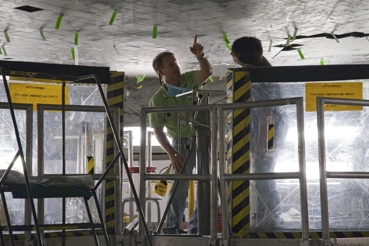 CAPE CANAVERAL, Fla. -- In Orbiter Processing Facility-2 at NASA's Kennedy Space Center in Florida, a thermal protection system technician points to an area on space shuttle Endeavour's underside that may require tile replacement.        As the final planned mission of the Space Shuttle Program, Endeavour and its crew will deliver the Alpha Magnetic Spectrometer, as well as critical spare components to the station on the STS-134 mission targeted for launch Feb. 26, 2011. For more information visit, http://www.nasa.gov/mission_pages/shuttle/shuttlemissions/sts134/index.html. Photo credit: NASA/Frankie Martin
