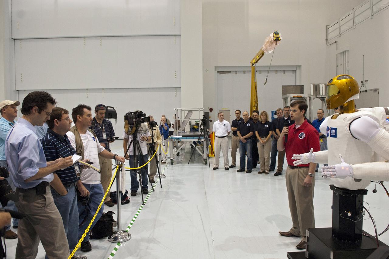 CAPE CANAVERAL, Fla. -- In the Space Station Processing Facility at NASA's Kennedy Space Center in Florida, Adam Sanders, General Motors robotics engineer, addresses the media at an event hosted by NASA to introduce the dexterous humanoid astronaut helper, Robonaut (R2) to the participants.                R2 will fly to the International Space Station aboard space shuttle Discovery on the STS-133 mission. Although it will initially only participate in operational tests, upgrades could eventually allow the robot to realize its true purpose -- helping spacewalking astronauts with tasks outside the space station. Photo credit: NASA/Jim Grossmann