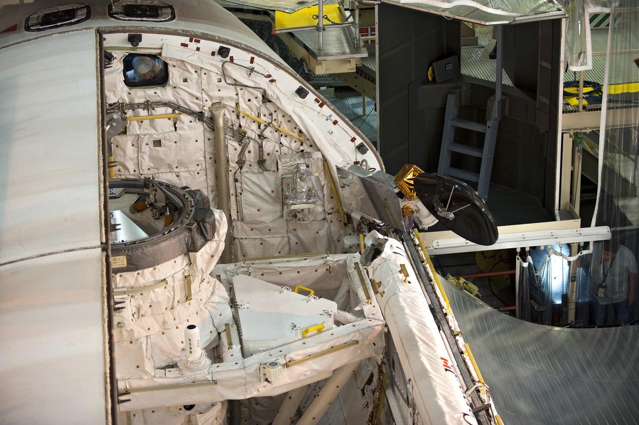 CAPE CANAVERAL, Fla. -- In Orbiter Processing Facility-3 at NASA's Kennedy Space Center in Florida, the Ku-band antenna is stored in space shuttle Discovery's payload bay. The antenna, which resembles a mini-satellite dish, transmits audio, video and data between Earth and the shuttle. Next, the clamshell doors of the payload bay will close completely in preparation for its move to the Vehicle Assembly Building next month. There, it will be attached to its external fuel tank and a set of solid rocket boosters for launch on the STS-133 mission to the International Space Station.    Targeted to launch Nov. 1, STS-133 will carry the multipurpose logistics module, or PMM, packed with supplies and critical spare parts, as well as Robonaut 2, or R2, to the station. Discovery will leave the module behind so it can be used for microgravity experiments in fluid physics, materials science, biology and biotechnology. Photo credit: NASA/Kim Shiflett