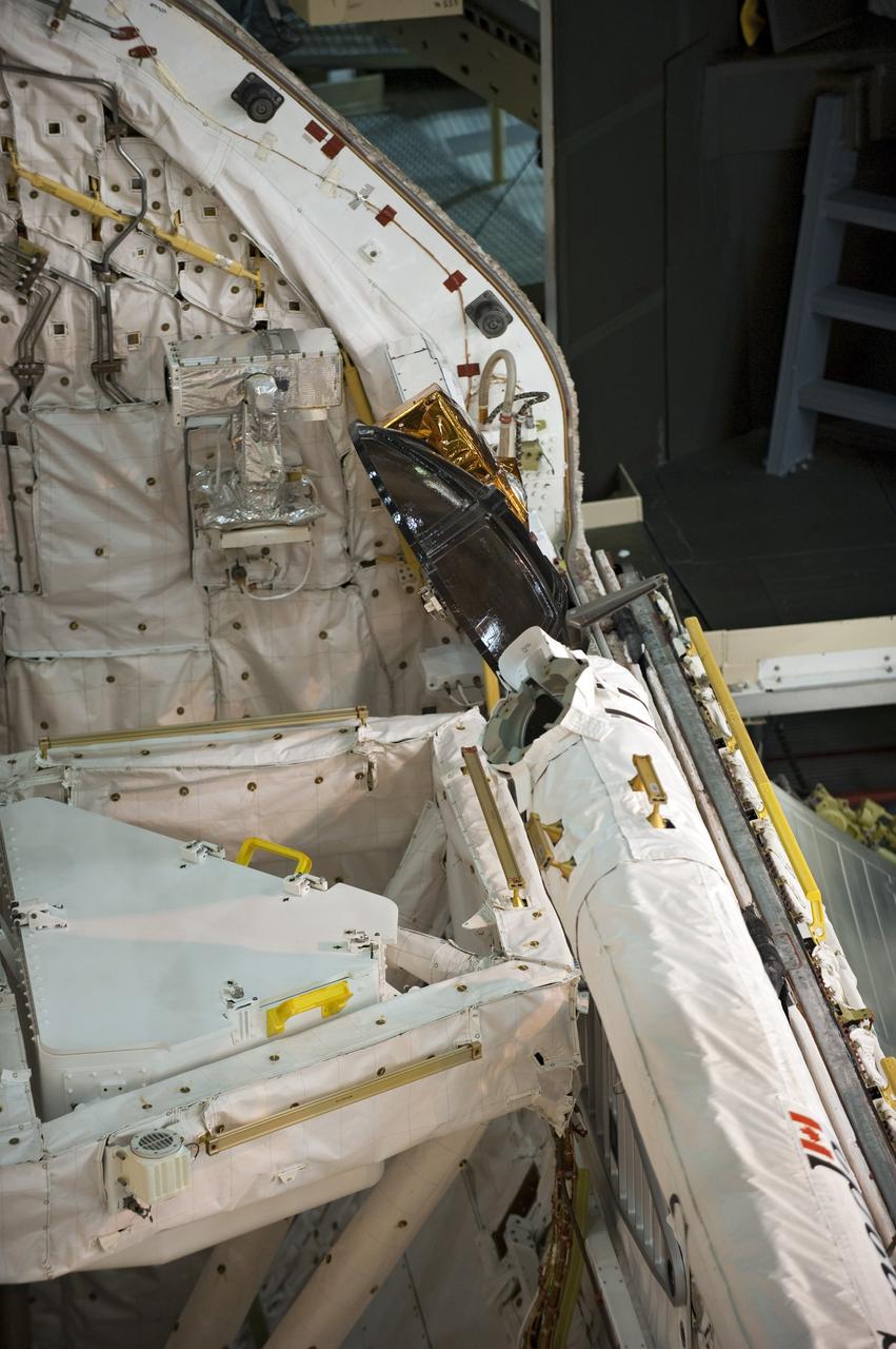 CAPE CANAVERAL, Fla. -- In Orbiter Processing Facility-3 at NASA's Kennedy Space Center in Florida, the Ku-band antenna is stored in space shuttle Discovery's payload bay. The antenna, which resembles a mini-satellite dish, transmits audio, video and data between Earth and the shuttle. Next, the clamshell doors of the payload bay will close completely in preparation for its move to the Vehicle Assembly Building next month. There, it will be attached to its external fuel tank and a set of solid rocket boosters for launch on the STS-133 mission to the International Space Station.    Targeted to launch Nov. 1, STS-133 will carry the multipurpose logistics module, or PMM, packed with supplies and critical spare parts, as well as Robonaut 2, or R2, to the station. Discovery will leave the module behind so it can be used for microgravity experiments in fluid physics, materials science, biology and biotechnology. Photo credit: NASA/Kim Shiflett