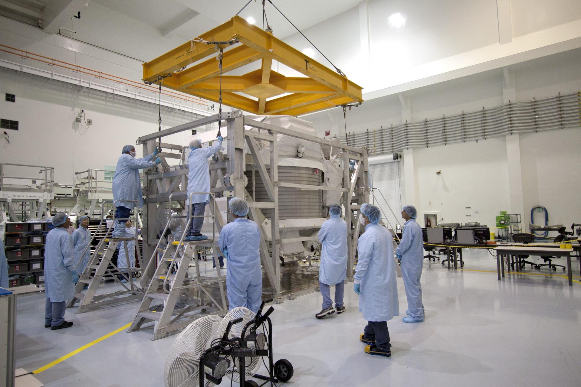 Technicians in the Space Station Processing Facility at NASA's Kennedy Space Center in Florida, attach an overhead crane to the Alpha Magnetic Spectrometer, or AMS, so it can be lifted onto a work stand and processed for launch.