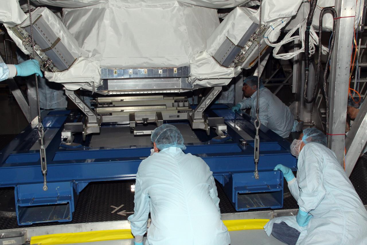 CAPE CANAVERAL, Fla. -- Technicians in the Space Station Processing Facility at NASA's Kennedy Space Center in Florida, check the progress of the Payload Attach System, or PAS, as it is lifted up to the Alpha Magnetic Spectrometer, where it will be attached to the bottom of the AMS. The PAS provides a method of securely connecting the payload to the International Space Station.      AMS, a state-of-the-art particle physics detector, is designed to operate as an external module on the International Space Station. It will use the unique environment of space to study the universe and its origin by searching for dark matter. AMS will fly to the station aboard space shuttle Endeavour's STS-134 mission targeted to launch Feb. 26, 2011. Photo credit: NASA/Jack Pfaller