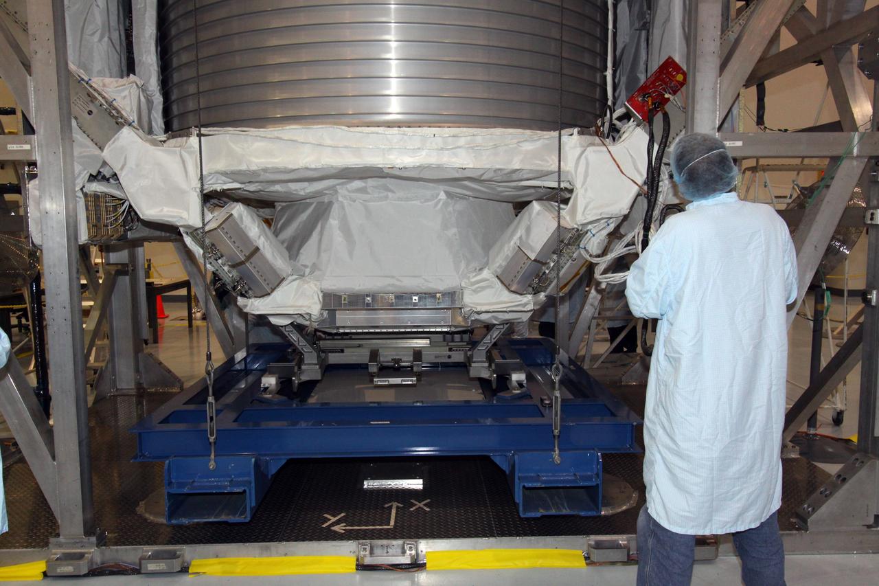 CAPE CANAVERAL, Fla. -- In the Space Station Processing Facility at NASA's Kennedy Space Center in Florida, a technician monitors the progress of the Payload Attach System, or PAS, as it is lifted up to the Alpha Magnetic Spectrometer, or AMS, where it will be attached to the bottom of the AMS. The PAS provides a method of securely connecting the payload to the International Space Station.      AMS, a state-of-the-art particle physics detector, is designed to operate as an external module on the International Space Station. It will use the unique environment of space to study the universe and its origin by searching for dark matter. AMS will fly to the station aboard space shuttle Endeavour's STS-134 mission targeted to launch Feb. 26, 2011. Photo credit: NASA/Jack Pfaller