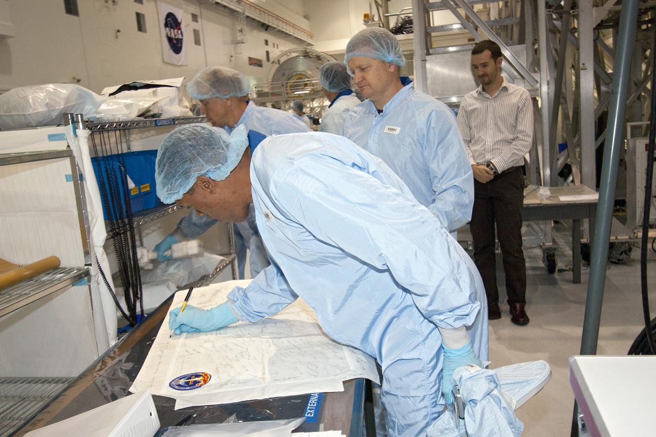 CAPE CANAVERAL, Fla. -- In the Space Station Processing Facility at NASA's Kennedy Space Center in Florida, STS-133 Mission Specialist Alvin Drew signs his name on a flag that will be flown on the mission, while Pilot Eric Boe looks on. The astronauts are at Kennedy to participate in the Payload Crew Equipment Interface Test, or CEIT, which gives the crew an opportunity for hands-on training with tools they'll be using in space and familiarization of the payload they will be delivering to the International Space Station. Launch of space shuttle Discovery is targeted for Nov. 1 at 4:40 p.m. EDT. For more information visit, www.nasa.gov/shuttle. Photo credit: NASA/Jack Pfaller
