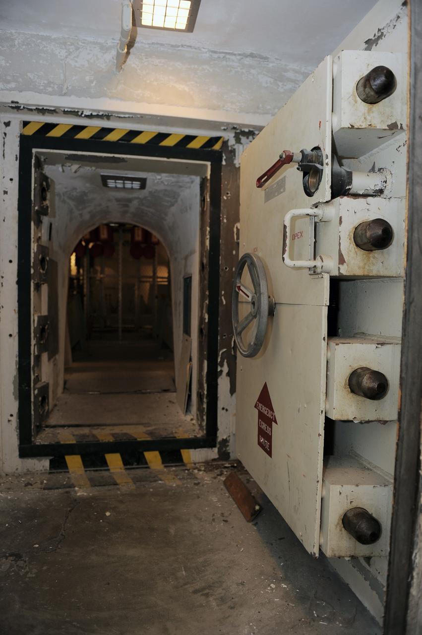 CAPE CANAVERAL, Fla. -- A steel door, similar to a bank vault door, leads to the blast-resistant "rubber room" beneath Launch Pad 39B at NASA's Kennedy Space Center. The room is a steel dome floating on rubber isolators and was used as an escape route during the Apollo Program in case of an emergency. It has since been abandoned by astronauts, but throughout the years nature found its way inside, including raccoons, snakes, birds and even a bobcat and opossum.    Starting in 2009, the structure above the room on the pad was no longer needed for NASA's Space Shuttle Program, so it is being restructured for future use. The new design will feature a "clean pad" for rockets to come with their own launcher, making it more versatile for a number of vehicles. For information on NASA's future plans, visit www.nasa.gov. Photo credit: NASA/Kim Shiflett