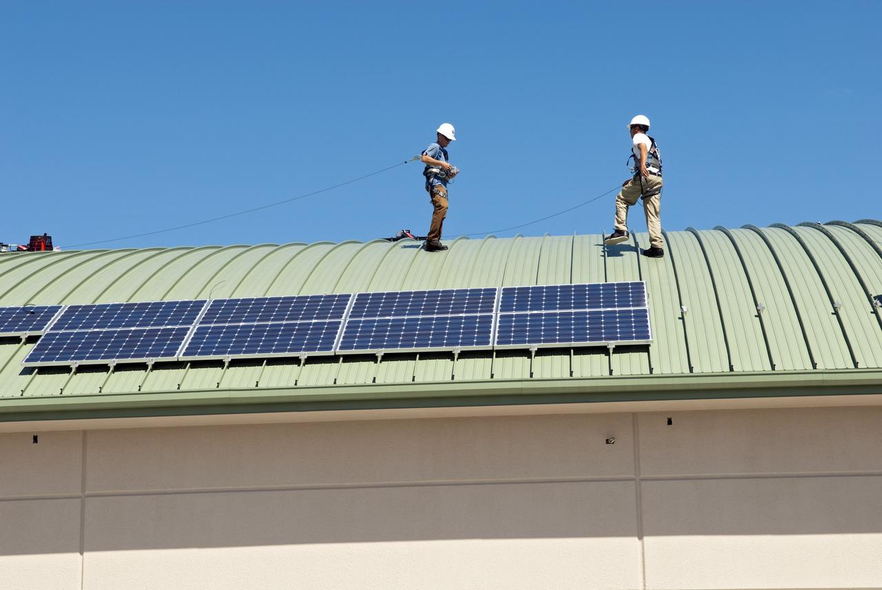 CAPE CANAVERAL, Fla. - Workers of Superior Solar LLC in Longwood, Fla., begin to install more than 300 solar panels on the roof of the Propellants North Administrative and Maintenance Facility at NASA's Kennedy Space Center in Florida. Each panel, built in Sharp Corp.'s Memphis, Tenn., plant, will produce 235 watts of clean energy. The green facility in Kennedy's Launch Complex 39 area will have a two-story administrative building to house managers, mechanics and technicians who fuel spacecraft at Kennedy adjacent to a single-story shop to store cryogenic fuel transfer equipment.     The facility is striving to qualify for the U.S. Green Building Council’s Leadership in Energy and Environmental Design (LEED) Platinum certification. If successful, it will be the first NASA facility to achieve this highest of LEED ratings after it is completed. The facility was designed for NASA by Jones Edmunds and Associates. H. W. Davis Construction is the construction contractor. Photo credit: NASA/Jim Grossmann