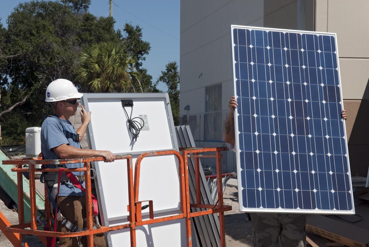 CAPE CANAVERAL, Fla. - Workers of Superior Solar LLC in Longwood, Fla., prepare to install more than 300 solar panels on the roof of the Propellants North Administrative and Maintenance Facility at NASA's Kennedy Space Center in Florida. Each panel, built in Sharp Corp.'s Memphis, Tenn., plant, will produce 235 watts of clean energy. The green facility in Kennedy's Launch Complex 39 area will have a two-story administrative building to house managers, mechanics and technicians who fuel spacecraft at Kennedy adjacent to a single-story shop to store cryogenic fuel transfer equipment.     The facility is striving to qualify for the U.S. Green Building Council’s Leadership in Energy and Environmental Design (LEED) Platinum certification. If successful, it will be the first NASA facility to achieve this highest of LEED ratings after it is completed. The facility was designed for NASA by Jones Edmunds and Associates. H. W. Davis Construction is the construction contractor. Photo credit: NASA/Jim Grossmann