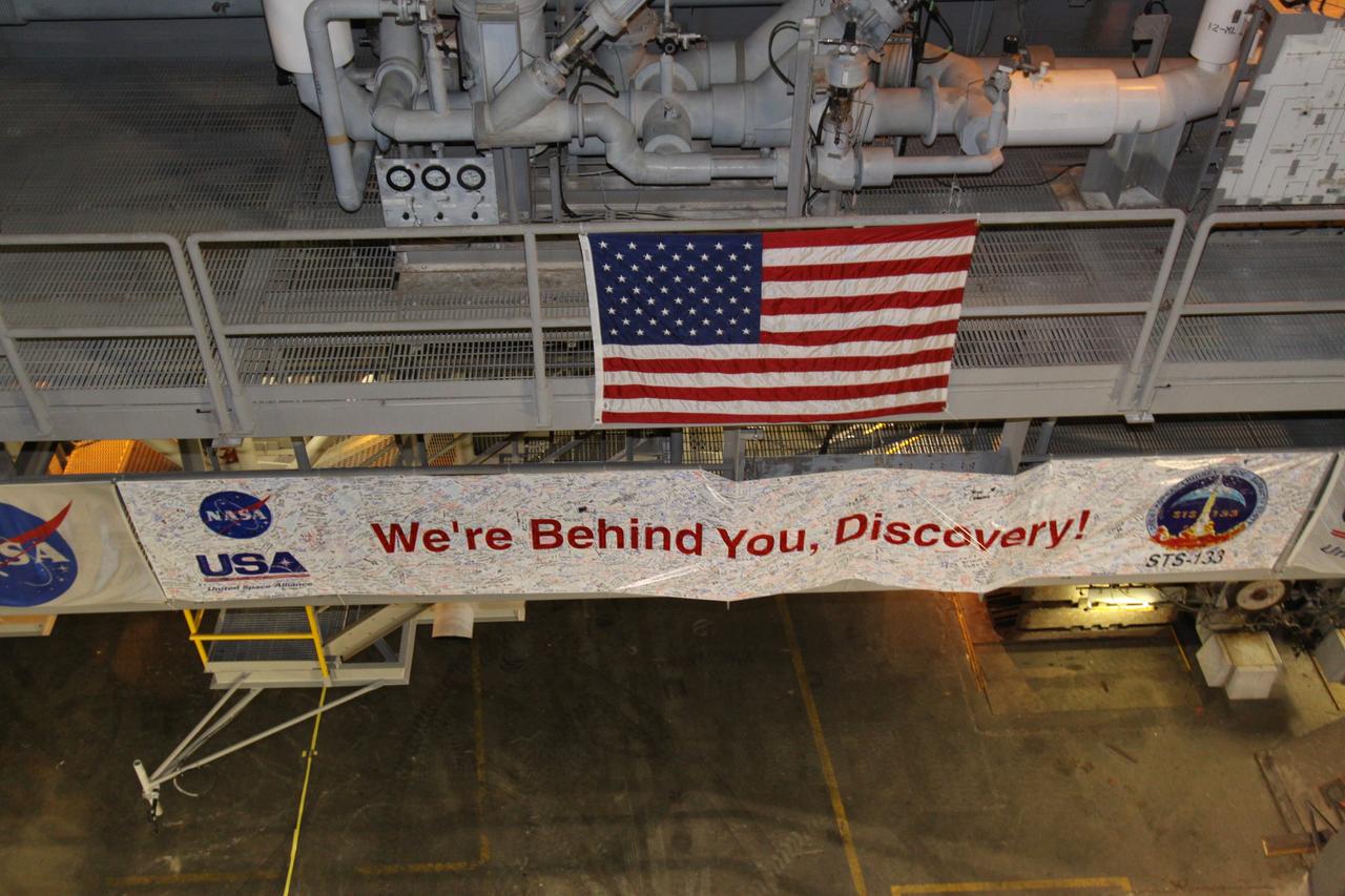 CAPE CANAVERAL, Fla. -- At NASA's Kennedy Space Center in Florida, an American flag and a sign supporting space shuttle Discovery with signatures of space center workers hang on its crawler-transporter mobile launcher as it begins the nighttime trek, known as "rollout," from the Vehicle Assembly Building to Launch Pad 39A. It will take the shuttle about six hours to complete the move. Rollout sets the stage for Discovery's STS-133 crew to practice countdown and launch procedures during the Terminal Countdown Demonstration Test in mid-October. Targeted to liftoff Nov. 1, Discovery will take the Permanent Multipurpose Module (PMM) packed with supplies and critical spare parts, as well as Robonaut 2 (R2) to the International Space Station. Photo credit: NASA/Jack Pfaller