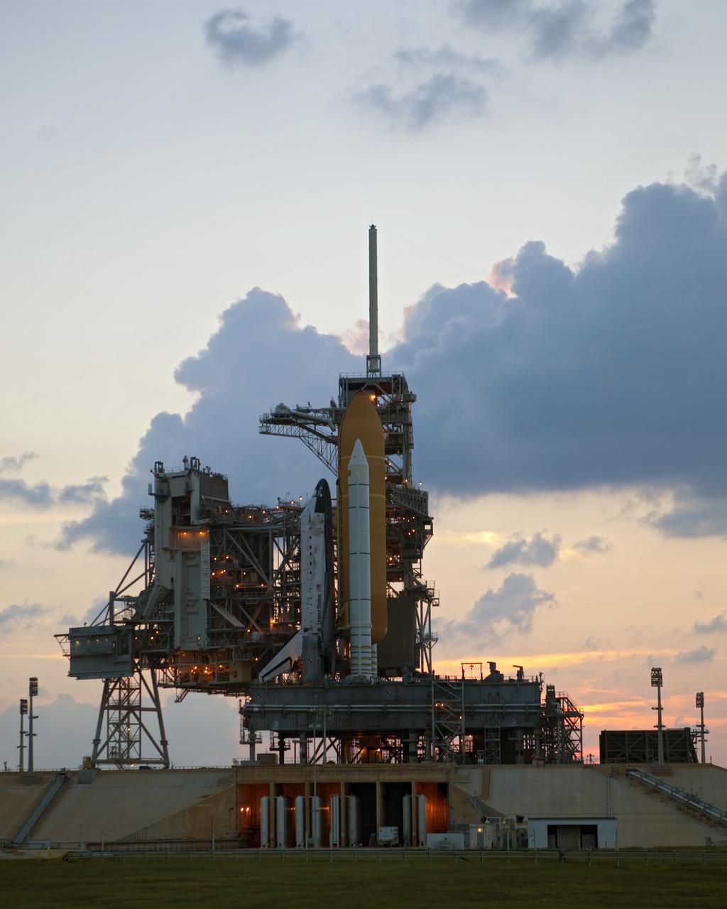 CAPE CANAVERAL, Fla. -- Space shuttle Discovery stands tall on Launch Pad 39A as the sun sets over NASA's Kennedy Space Center in Florida. Meanwhile, space center workers are preparing to move the rotating service structure into place. The structure protects the shuttle from the elements and allows access into the spacecraft while on the pad. Targeted to liftoff Nov. 1, Discovery will take the Permanent Multipurpose Module (PMM) packed with supplies and critical spare parts, as well as Robonaut 2 (R2) to the International Space Station on the STS-133 mission. Photo credit: NASA/Dimitri Gerondidakis
