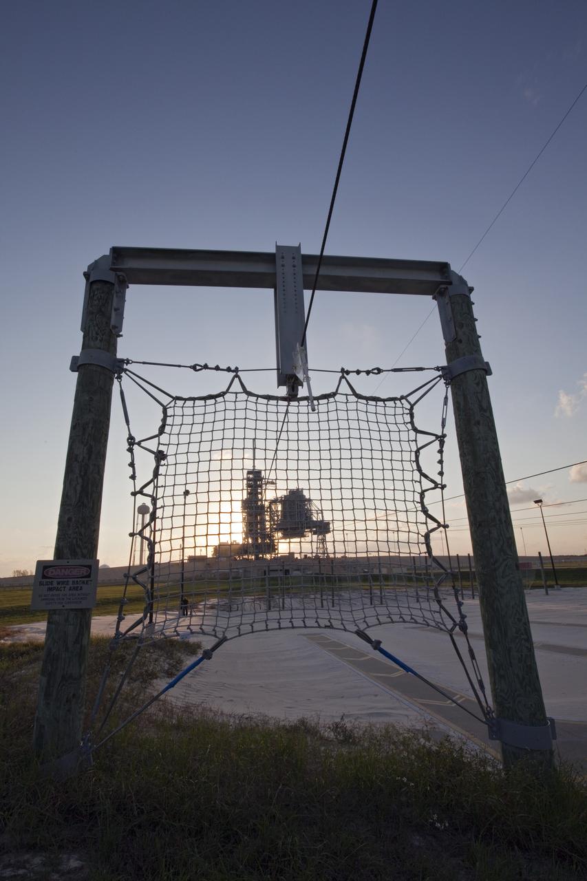 CAPE CANAVERAL, Fla. -- Launch Pad 39A, which is attached to space shuttle Discovery, is seen through a slide wire basket as the sun rises over NASA's Kennedy Space Center in Florida. Later, the rotating service structure that protects the shuttle from the elements and provides access inside the vehicle will be moved into place. It took the spacecraft about six hours to make the journey, known as "rollout," from the Vehicle Assembly Building to the pad. Rollout sets the stage for Discovery's STS-133 crew to practice countdown and launch procedures during the Terminal Countdown Demonstration Test in mid-October. Targeted to liftoff Nov. 1, Discovery will take the Permanent Multipurpose Module (PMM) packed with supplies and critical spare parts, as well as Robonaut 2 (R2) to the International Space Station. Photo credit: NASA/Frankie Martin