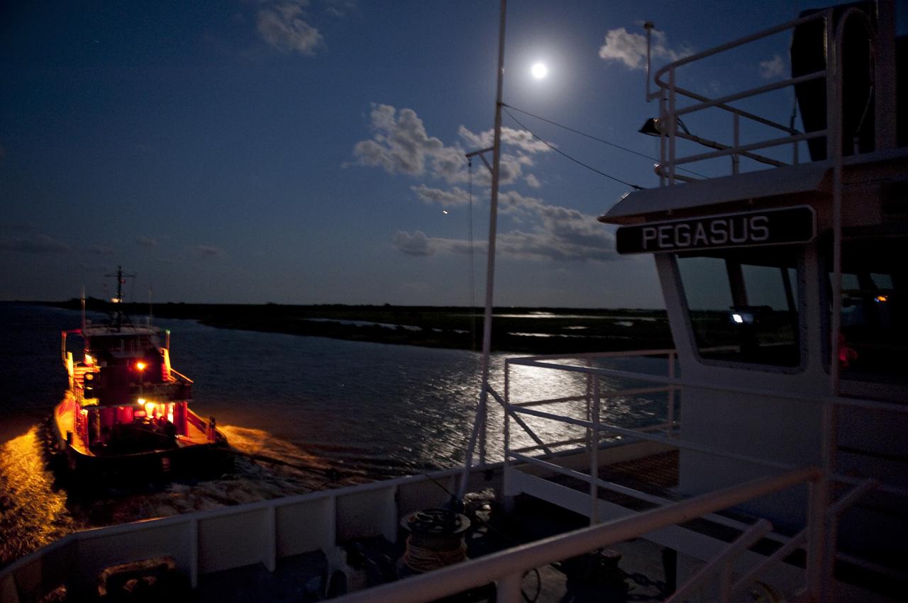NEW ORLEANS -- As the moon lights up the water, as tug boat pulls the Pegasus Barge  carrying the Space Shuttle Program's last external fuel tank, ET-122, from NASA's Michoud Assembly Facility in New Orleans to NASA's Kennedy Space Center in Florida. The tank will travel 900 miles by sea before being offloaded and moved for Kennedy's Vehicle Assembly Building. There it will be integrated to space shuttle Endeavour for the STS-134 mission to the International Space Station.          The tank, which is the largest element of the space shuttle stack, was damaged during Hurricane Katrina in August 2005 and restored to flight configuration by Lockheed Martin Space Systems Company employees. STS-134, targeted to launch Feb. 2011, currently is scheduled to be the last mission in the Space Shuttle Program. Photo credit: NASA/Kim Shiflett