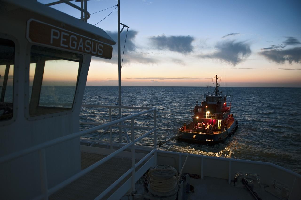 LOUISIANA -- A tug boat pulls the Pegasus Barge carrying the Space Shuttle Program's last external fuel tank, ET-122, from NASA's Michoud Assembly Facility in New Orleans toward Gulfport, La. The barge will meet up with Freedom Star, NASA's solid rocket booster retrieval ship, which will escort it to NASA's Kennedy Space Center in Florida. The tank will travel 900 miles by sea before being offloaded and moved to Kennedy's Vehicle Assembly Building. There it will be integrated to space shuttle Endeavour for the STS-134 mission to the International Space Station.            The tank, which is the largest element of the space shuttle stack, was damaged during Hurricane Katrina in August 2005 and restored to flight configuration by Lockheed Martin Space Systems Company employees. STS-134, targeted to launch Feb. 2011, currently is scheduled to be the last mission in the Space Shuttle Program. Photo credit: NASA/Kim Shiflett