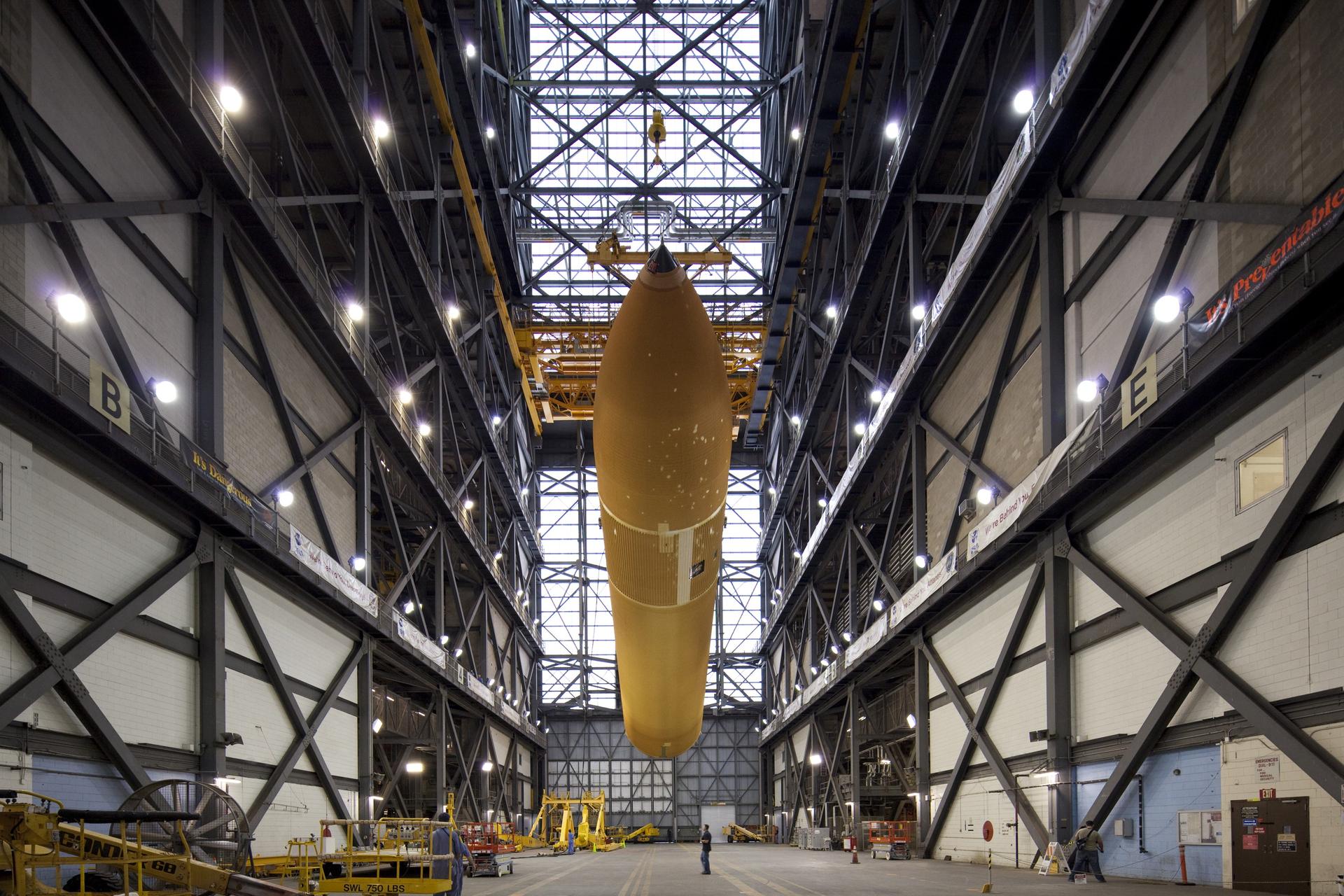 workers monitor the progress of External Fuel Tank-122 as it is lifted toward a test cell in the Vehicle Assembly Building