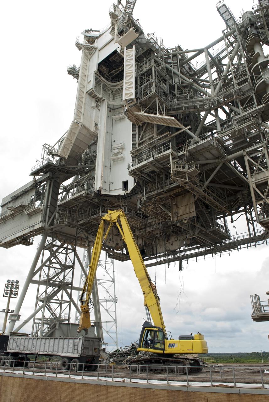 CAPE CANAVERAL, Fla. -- At NASA's Kennedy Space Center in Florida, crews are dismantling the rotating service structure (RSS) on Launch Pad 39B. Sand, reinforcing steel and large wooden mats were put down under the RSS to protect the structure's concrete from falling debris during deconstruction.          Starting in 2009, the structure at the pad was no longer needed for NASA's Space Shuttle Program, so it is being restructured for future use. The new design will feature a "clean pad" for rockets to come with their own launcher, making it more versatile for a number of vehicles. The new lightning protection system, consisting of three lightning towers and a wire catenary system will remain. Photo credit: NASA/Jim Grossmann
