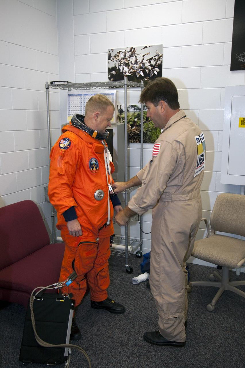 CAPE CANAVERAL, Fla. -- At NASA's Kennedy Space Center in Florida, STS-133 Pilot Eric Boe puts on his orange flight suit in the Shuttle Landing Facility's Landing Aids Control Building, which is on the south end of the facility's runway. Boe and Commander Steve Lindsey are preparing to practice landings in Shuttle Training Aircraft, modified Gulfstream II business jets that mimic the shuttle's handling during the final phase of landing. Practice landings are part of the Terminal Countdown Demonstration Test (TCDT), which provides each shuttle crew and launch team an opportunity to participate in various simulated activities, including equipment familiarization and emergency training at the launch pad.    Space shuttle Discovery and its STS-133 crew will deliver the Permanent Multipurpose Module, packed with supplies and critical spare parts, as well as Robonaut 2, the dexterous humanoid astronaut helper, to the International Space Station. Launch is targeted for Nov. 1 at 4:40 p.m. For more information on the STS-133 mission, visit www.nasa.gov/mission_pages/shuttle/shuttlemissions/sts133/. Photo credit: NASA/Jack Pfaller