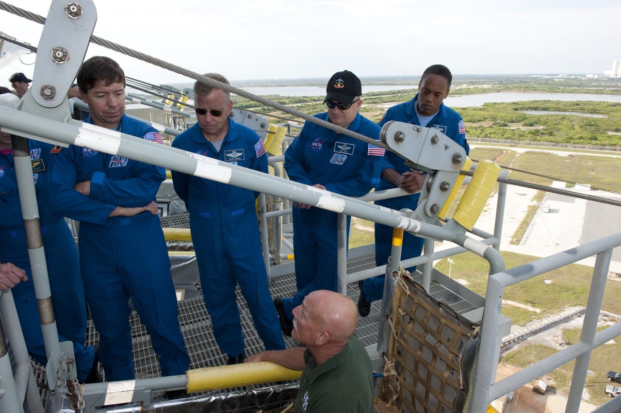 CAPE CANAVERAL, Fla. -- On Launch Pad 39A at NASA's Kennedy Space Center, STS-133 crew members receive instruction on the operation of the pad's slidewire basket system emergency exit training as part of the Terminal Countdown Demonstration Test (TCDT). From left are Mission Specialist Michael Barratt, Commander Steve Lindsey, Pilot Eric Boe and Mission Specialist Alvin Drew.      TCDT provides each shuttle crew and launch team an opportunity to participate in various simulated activities, including equipment familiarization and a launch countdown. Space shuttle Discovery and its STS-133 crew will deliver the Permanent Multipurpose Module, packed with supplies and critical spare parts, as well as Robonaut 2, the dexterous humanoid astronaut helper, to the International Space Station. Launch is targeted for Nov. 1 at 4:40 p.m. For more information on the STS-133 mission, visit www.nasa.gov/mission_pages/shuttle/shuttlemissions/sts133/. Photo credit: NASA/Kim Shiflett