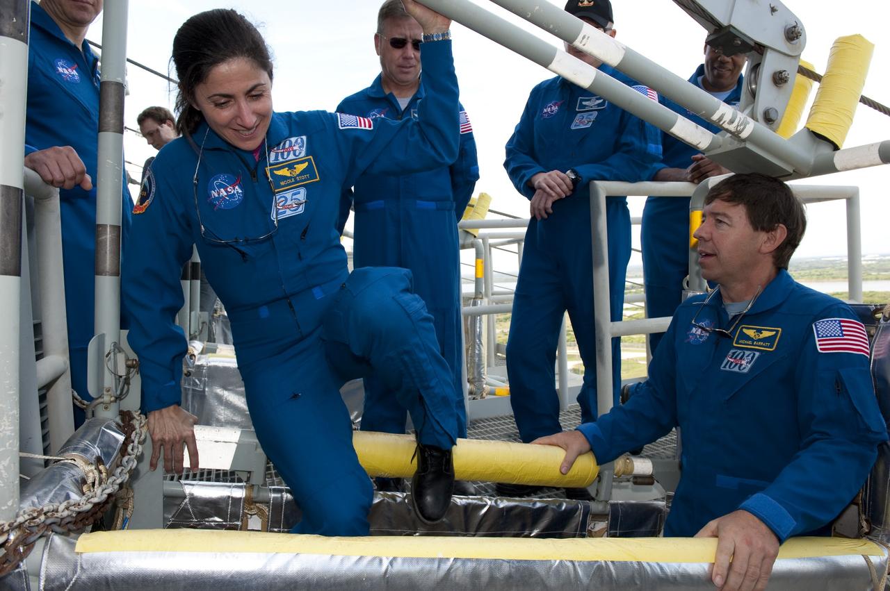 CAPE CANAVERAL, Fla. -- On Launch Pad 39A at NASA's Kennedy Space Center, STS-133 crew members receive instruction on the operation of the pad's slidewire basket system emergency exit training as part of the Terminal Countdown Demonstration Test (TCDT). Inside the basket are Mission Specialists Nicole Stott, left, and Michael Barratt. TCDT provides each shuttle crew and launch team an opportunity to participate in various simulated activities, including equipment familiarization and a launch countdown. Space shuttle Discovery and its STS-133 crew will deliver the Permanent Multipurpose Module, packed with supplies and critical spare parts, as well as Robonaut 2, the dexterous humanoid astronaut helper, to the International Space Station. Launch is targeted for Nov. 1 at 4:40 p.m. For more information on the STS-133 mission, visit www.nasa.gov/mission_pages/shuttle/shuttlemissions/sts133/. Photo credit: NASA/Kim Shiflett