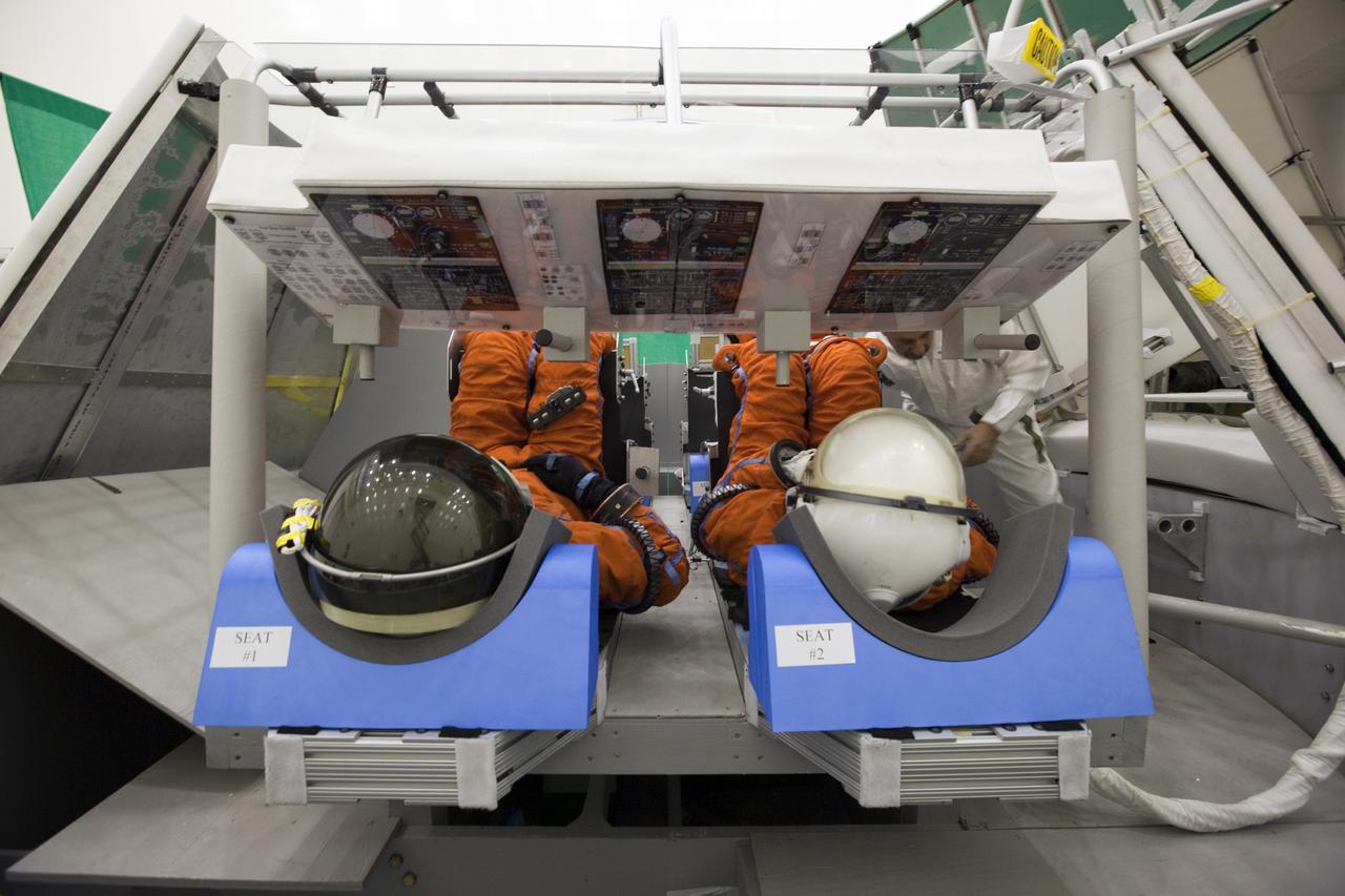 CAPE CANAVERAL, Fla. -- In the Multi-Payload Processing Facility at NASA's Kennedy Space Center in Florida, NASA astronauts Shane Kimbrough, left, and Marsha Ivins, participate in an exercise known as crew egress evaluation from an Orion mock-up. The spacecraft is replicated in all areas that could affect a crew's escape, including the area that seals to a launch pad's White Room. The exercise focuses on whether astronauts and their rescue crews can exit the vehicle quickly in the event of a pad emergency. For more information on Orion, visit www.nasa.gov/orion. Photo credit: NASA/Dimitri Gerondidakis