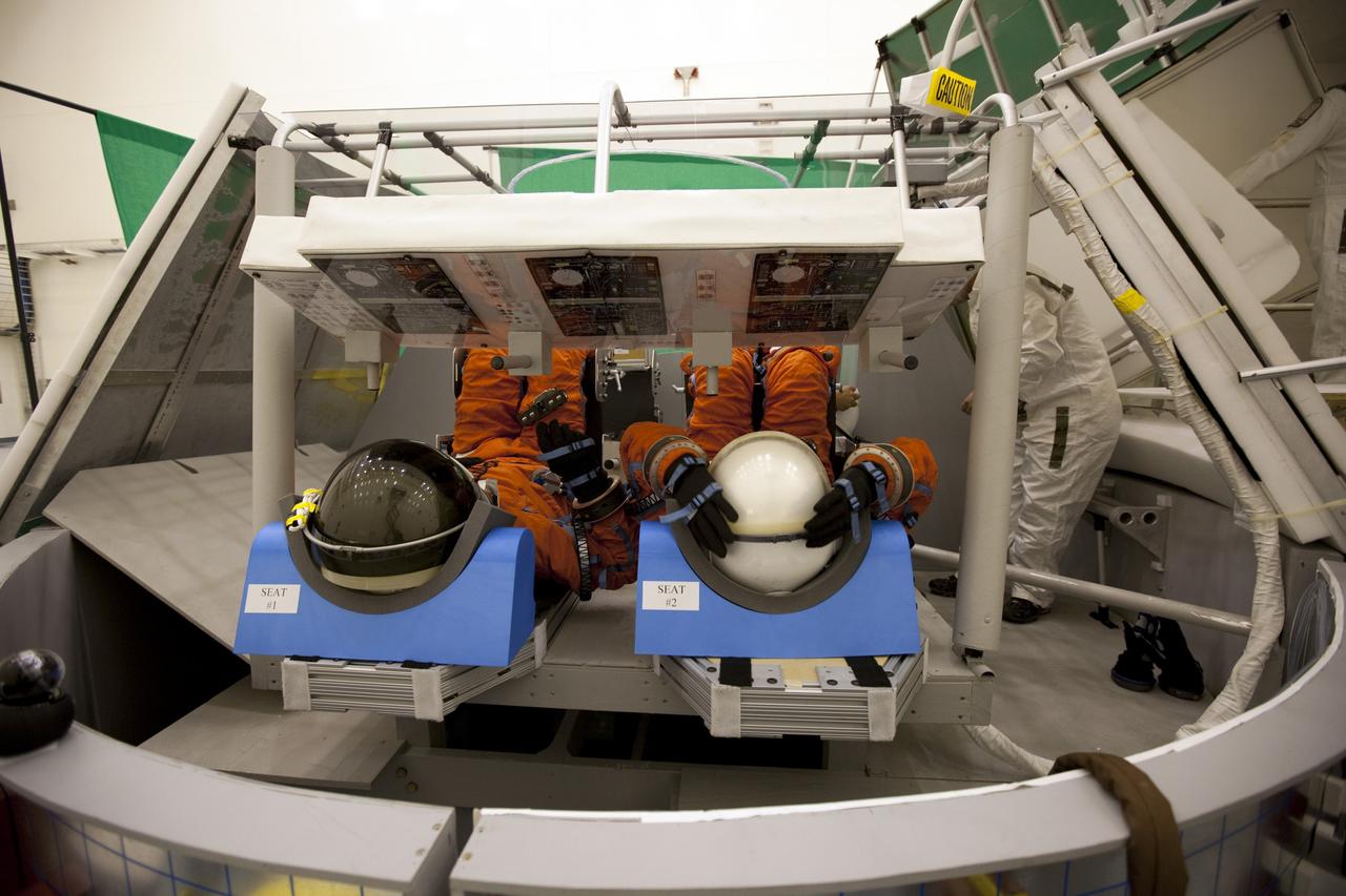 CAPE CANAVERAL, Fla. -- In the Multi-Payload Processing Facility at NASA's Kennedy Space Center in Florida, NASA astronauts Shane Kimbrough, left, and Marsha Ivins, participate in an exercise known as crew egress evaluation from an Orion mock-up. The spacecraft is replicated in all areas that could affect a crew's escape, including the area that seals to a launch pad's White Room. The exercise focuses on whether astronauts and their rescue crews can exit the vehicle quickly in the event of a pad emergency. For more information on Orion, visit www.nasa.gov/orion. Photo credit: NASA/Dimitri Gerondidakis