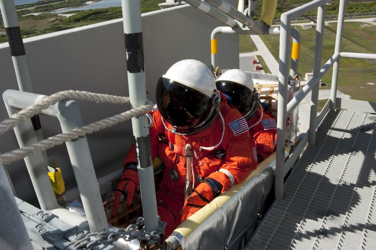 CAPE CANAVERAL, Fla. -- During a simulated pad emergency on Launch Pad 39A at NASA's Kennedy Space Center in Florida, STS-133 Mission Specialists Michael Barratt, left, and Nicole Stott hop in a slidewire basket that would take them to a safe bunker below the pad in an unlikely emergency situation. The emergency training while aboard space shuttle Discovery is part of a week-long Terminal Countdown Demonstration Test (TCDT).        Discovery and its STS-133 crew will deliver the Permanent Multipurpose Module, packed with supplies and critical spare parts, as well as Robonaut 2, the dexterous humanoid astronaut helper, to the International Space Station. Launch is targeted for Nov. 1 at 4:40 p.m. For more information on the STS-133 mission, visit www.nasa.gov/mission_pages/shuttle/shuttlemissions/sts133/. Photo credit: NASA/Kim Shiflett
