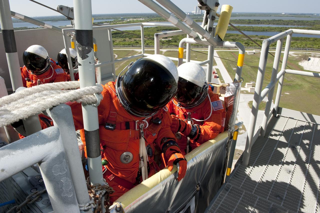 CAPE CANAVERAL, Fla. -- During a simulated pad emergency on Launch Pad 39A at NASA's Kennedy Space Center in Florida, STS-133 Mission Specialists Alvin Drew, front left, and Tim Kopra hop in a slidewire basket that would take them to a safe bunker below the pad in an unlikely emergency situation. The emergency training while aboard space shuttle Discovery is part of a week-long Terminal Countdown Demonstration Test (TCDT). Discovery and its STS-133 crew will deliver the Permanent Multipurpose Module, packed with supplies and critical spare parts, as well as Robonaut 2, the dexterous humanoid astronaut helper, to the International Space Station. Launch is targeted for Nov. 1 at 4:40 p.m. For more information on the STS-133 mission, visit www.nasa.gov/mission_pages/shuttle/shuttlemissions/sts133/. Photo credit: NASA/Kim Shiflett