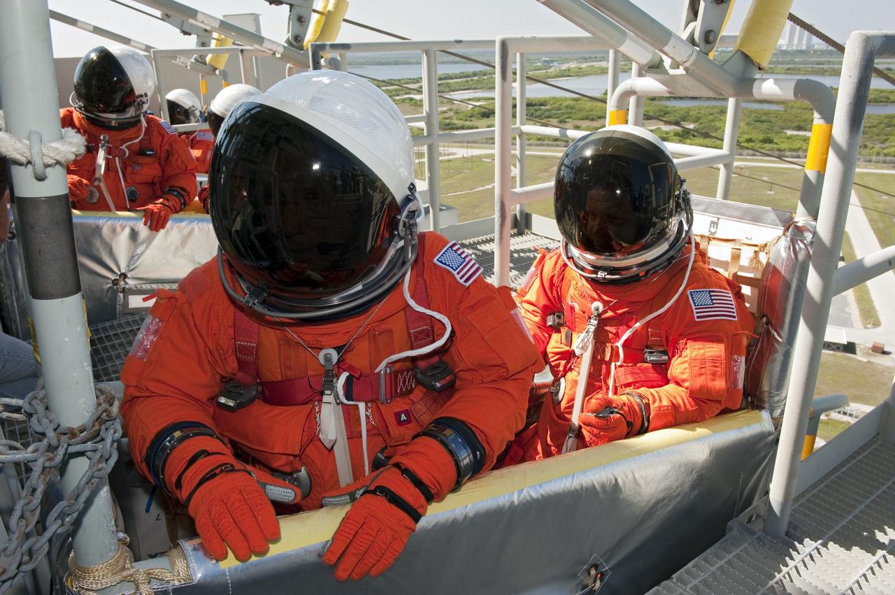CAPE CANAVERAL, Fla. -- During a simulated pad emergency on Launch Pad 39A at NASA's Kennedy Space Center in Florida, STS-133 Commander Steve Lindsey, front left, and Pilot Eric Boe hop in a slidewire basket that would take them to a safe bunker below the pad in an unlikely emergency situation. The emergency training while aboard space shuttle Discovery is part of a week-long Terminal Countdown Demonstration Test (TCDT).      Discovery and its STS-133 crew will deliver the Permanent Multipurpose Module, packed with supplies and critical spare parts, as well as Robonaut 2, the dexterous humanoid astronaut helper, to the International Space Station. Launch is targeted for Nov. 1 at 4:40 p.m. For more information on the STS-133 mission, visit www.nasa.gov/mission_pages/shuttle/shuttlemissions/sts133/. Photo credit: NASA/Kim Shiflett