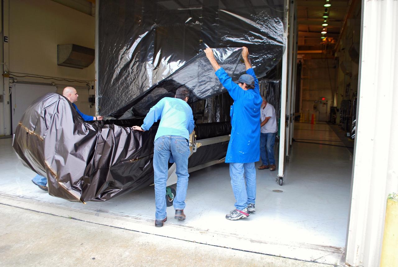 VANDENBERG AIR FORCE BASE, Calif. – At Vandenberg Air Force Base in California, the second half of the fairing that will encapsulate NASA's Glory satellite during launch aboard a Taurus XL rocket is moved into Building 1555. There, the black protective covering will be removed so that the fairing half can be thoroughly cleaned before it is installed around the spacecraft. The four-stage rocket and satellite are being prepared for a launch to low Earth orbit from Vandenberg's Space Launch Complex 576-E.        Once Glory reaches orbit, it will collect data on the properties of aerosols and black carbon. It also will help scientists understand how the sun's irradiance affects Earth's climate. Photo credit: NASA/Randy Beaudoin, VAFB