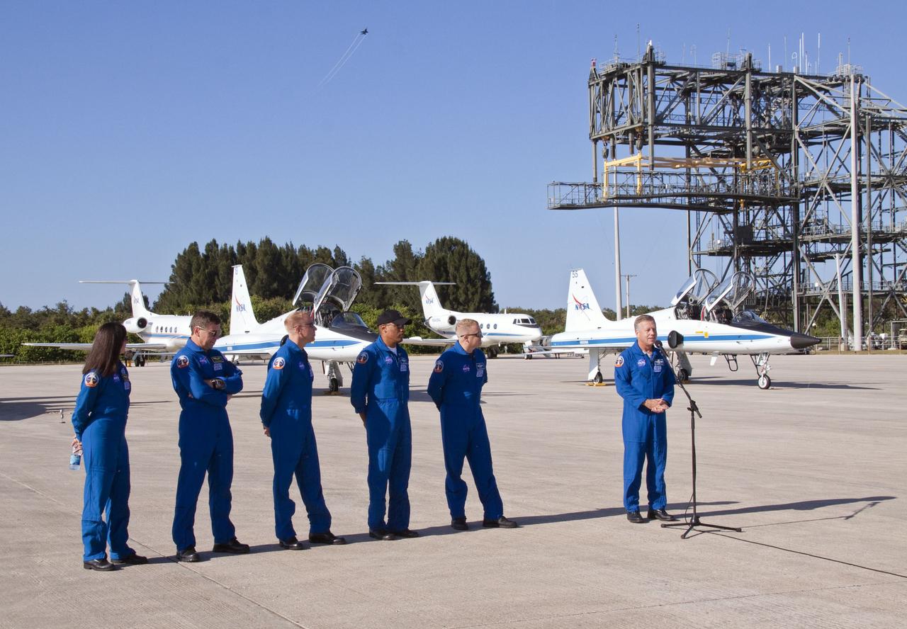 CAPE CANAVERAL, Fla. -- At NASA's Kennedy Space Center in Florida, space shuttle Discovery's STS-133 crew addresses the media on the Shuttle Landing Facility runway after arriving aboard T-38 training jets. From left are Mission Specialists Nicole Stott, Michael Barratt, Tim Kopra and Alvin Drew, Pilot Eric Boe, and Commander Steve Lindsey. Flying high above the crew is an F-15, participating in an Air Force Week celebration at the center's Visitor Complex. In the days leading up to their launch to the International Space Station, the crew members will check the fit of their launch-and-entry suits, review launch-day procedures, receive weather briefings and remain medically quarantined to prevent sickness.      Scheduled to lift off Nov. 1 at 4:40 p.m., Discovery and crew will deliver the Permanent Multipurpose Module, packed with supplies and critical spare parts, as well as Robonaut 2, the dexterous humanoid astronaut helper, to the orbiting outpost. For more information on the STS-133 mission, visit www.nasa.gov/mission_pages/shuttle/shuttlemissions/sts133/. Photo credit: NASA/Jack Pfaller