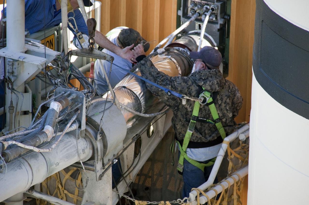 CAPE CANAVERAL, Fla. -- On Launch Pad 39A at NASA's Kennedy Space Center in Florida, workers prepare to begin removing the quick disconnect from the ground umbilical carrier plate (GUCP) on space shuttle Discovery's external fuel tank. A hydrogen gas leak at that location during tanking for the STS-133 mission to the International Space Station caused the launch attempt to be scrubbed Nov. 5. The GUCP will be examined to determine the cause of the hydrogen leak and then repaired. The GUCP is the overboard vent to the pad and the flame stack where the vented hydrogen is burned off. Discovery's next launch attempt is targeted for no earlier than Nov. 30 at 4:02 a.m. EST. For more information on STS-133, visit www.nasa.gov/mission_pages/shuttle/shuttlemissions/sts133/. Photo credit: NASA/Troy Cryder