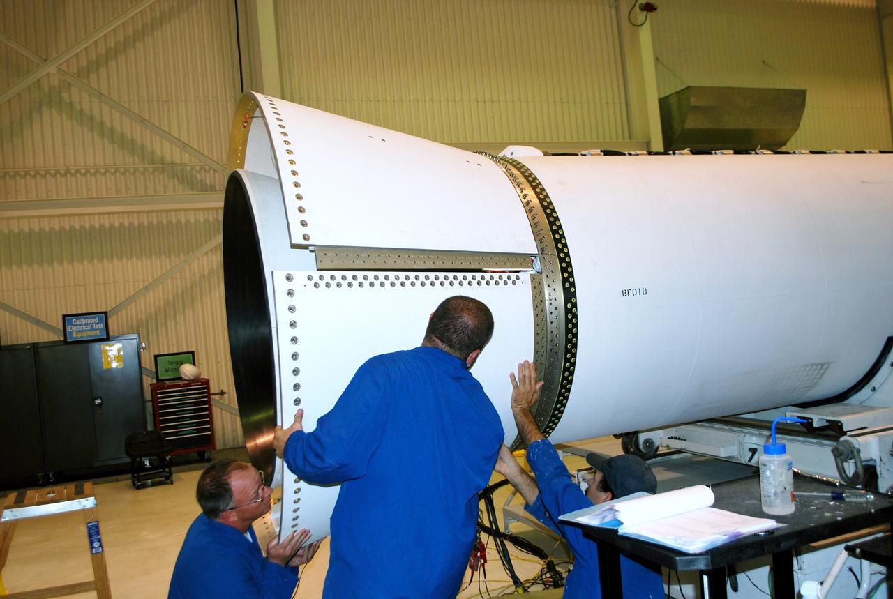 VANDENBERG AIR FORCE BASE, Calif. – In Building 1555 at Vandenberg Air Force Base in California, Orbital Sciences Corp. technicians install the second petal to the aft end of the Taurus XL rocket's first stage motor. Three pedals will essentially make up the aft skirt of the first stage, covering and protecting a myriad of cabling.    The Orbital Sciences Taurus XL rocket, targeted to lift off Feb. 23, 2011, from Vandenberg's Space Launch Complex 576-E, will take NASA's Glory satellite into low Earth. Glory is scheduled to collect data on the properties of aerosols and black carbon. It also will help scientists understand how the sun's irradiance affects Earth's climate.  Photo credit: NASA/Randy Beaudoin, VAFB