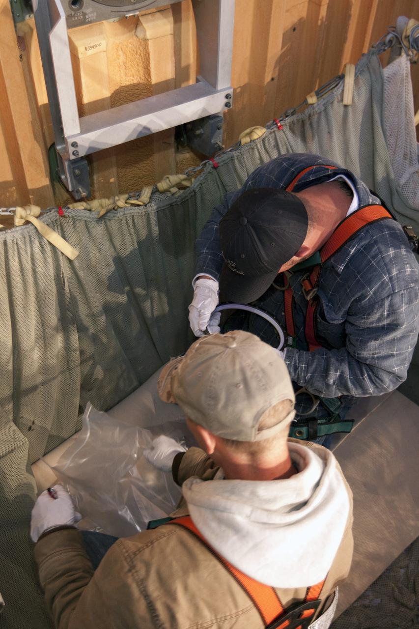 CAPE CANAVERAL, Fla. -- On Launch Pad 39A at NASA's Kennedy Space Center in Florida, workers examine the seal from the ground umbilical carrier plate (GUCP). A hydrogen gas leak at that location on the external fuel tank during tanking for space shuttle Discovery's STS-133 mission to the International Space Station caused the launch attempt to be scrubbed Nov. 5. The GUCP will be examined to determine the cause of the hydrogen leak and then repaired. The GUCP is the overboard vent to the pad and the flame stack where the excess hydrogen is burned off.       For more information on STS-133, visit www.nasa.gov/mission_pages/shuttle/shuttlemissions/sts133/. Photo credit: NASA/Jack Pfaller