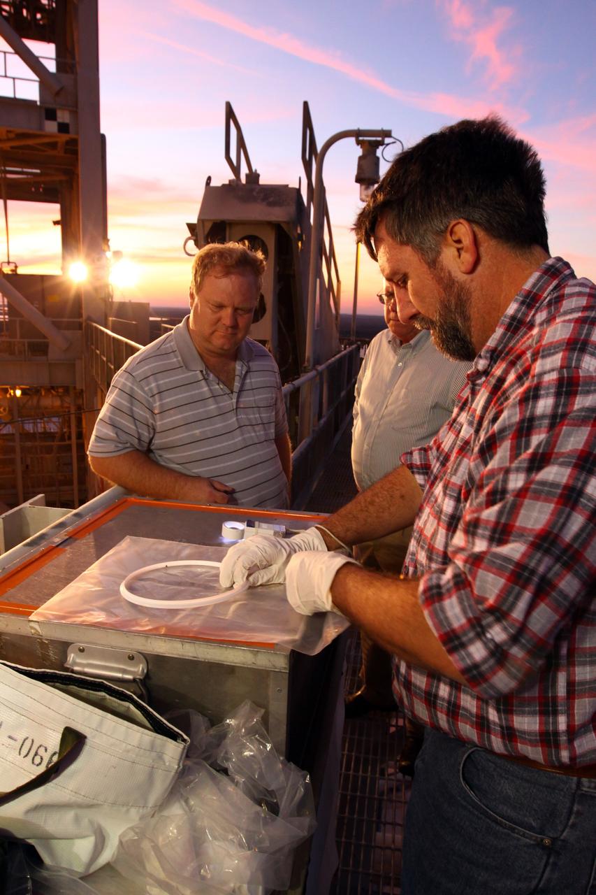CAPE CANAVERAL, Fla. -- On Launch Pad 39A at NASA's Kennedy Space Center in Florida, workers examine the seal from the ground umbilical carrier plate (GUCP). A hydrogen gas leak at that location on the external fuel tank during tanking for space shuttle Discovery's STS-133 mission to the International Space Station caused the launch attempt to be scrubbed Nov. 5. The GUCP will be examined to determine the cause of the hydrogen leak and then repaired. The GUCP is the overboard vent to the pad and the flame stack where the excess hydrogen is burned off.     For more information on STS-133, visit www.nasa.gov/mission_pages/shuttle/shuttlemissions/sts133/.     Photo credit: NASA/Jack Pfaller