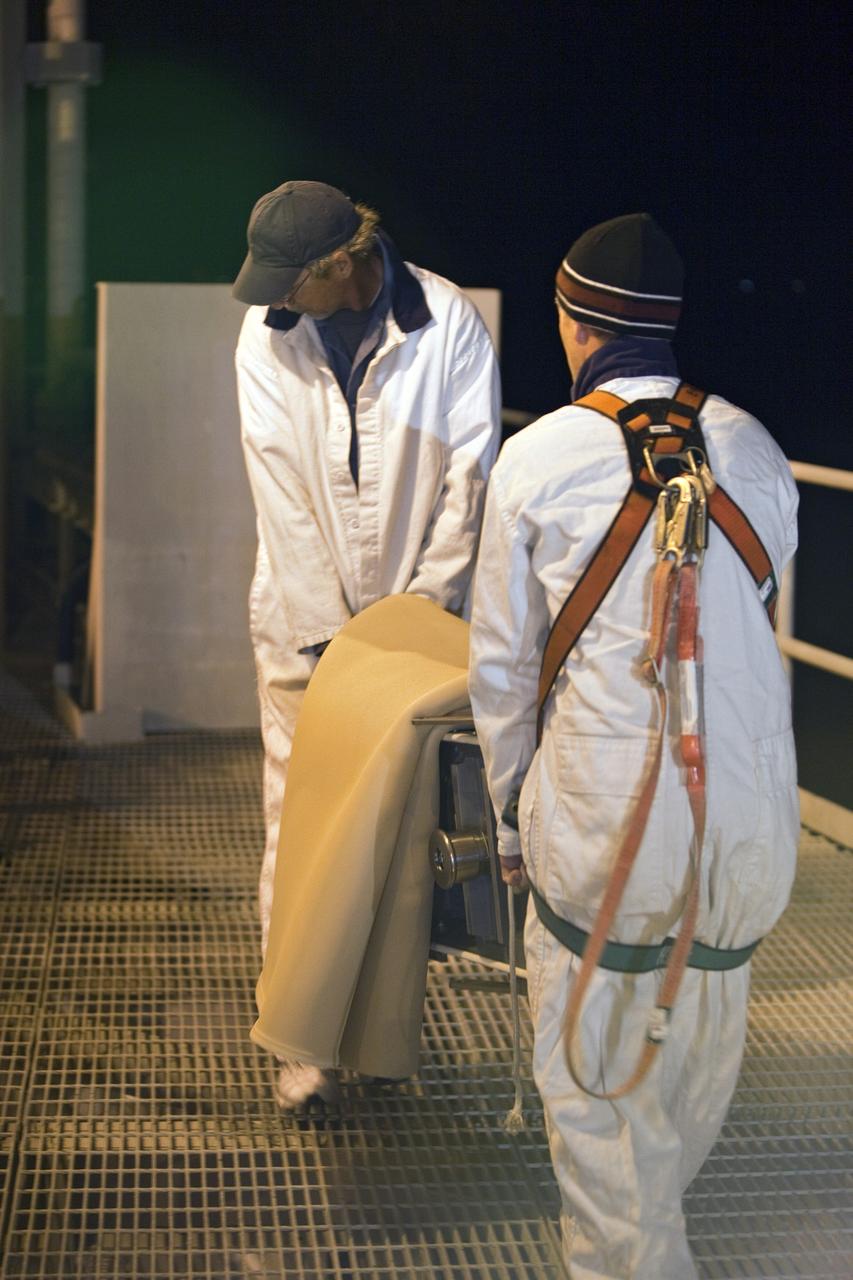 CAPE CANAVERAL, Fla. -- On Launch Pad 39A at NASA's Kennedy Space Center in Florida, workers move the ground umbilical carrier plate (GUCP) to a location where it can be examined. A hydrogen gas leak at that location on the external fuel tank during tanking for space shuttle Discovery's STS-133 mission to the International Space Station caused the launch attempt to be scrubbed Nov. 5. The GUCP will be examined to determine the cause of the hydrogen leak and then repaired. The GUCP is the overboard vent to the pad and the flame stack where the excess hydrogen is burned off.         For more information on STS-133, visit www.nasa.gov/mission_pages/shuttle/shuttlemissions/sts133/. Photo credit: NASA/Dimitri Gerondidakis