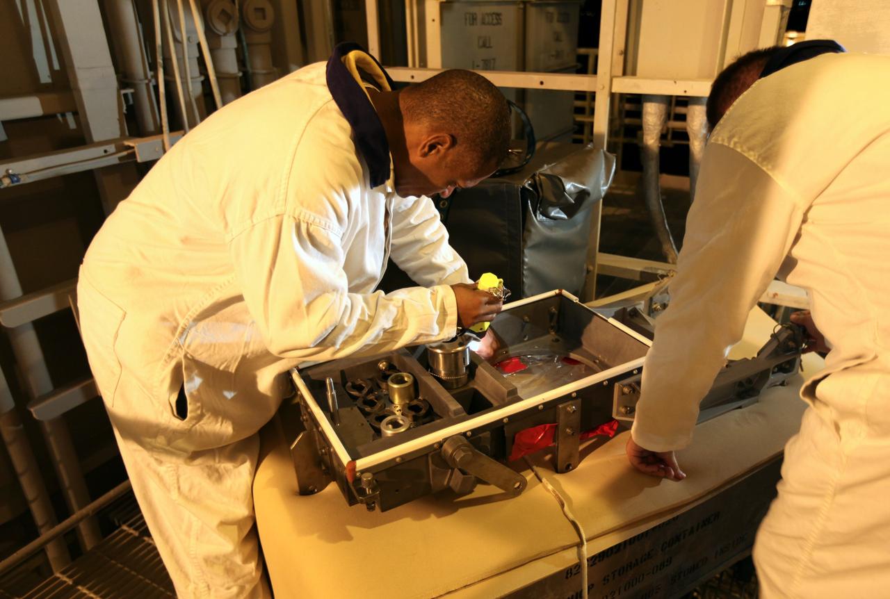 CAPE CANAVERAL, Fla. -- On Launch Pad 39A at NASA's Kennedy Space Center in Florida, workers examine the ground umbilical carrier plate (GUCP). A hydrogen gas leak at that location on the external fuel tank during tanking for space shuttle Discovery's STS-133 mission to the International Space Station caused the launch attempt to be scrubbed Nov. 5. The GUCP will be examined to determine the cause of the hydrogen leak and then repaired. The GUCP is the overboard vent to the pad and the flame stack where the excess hydrogen is burned off.       For more information on STS-133, visit www.nasa.gov/mission_pages/shuttle/shuttlemissions/sts133/. Photo credit: NASA/Dimitri Gerondidakis