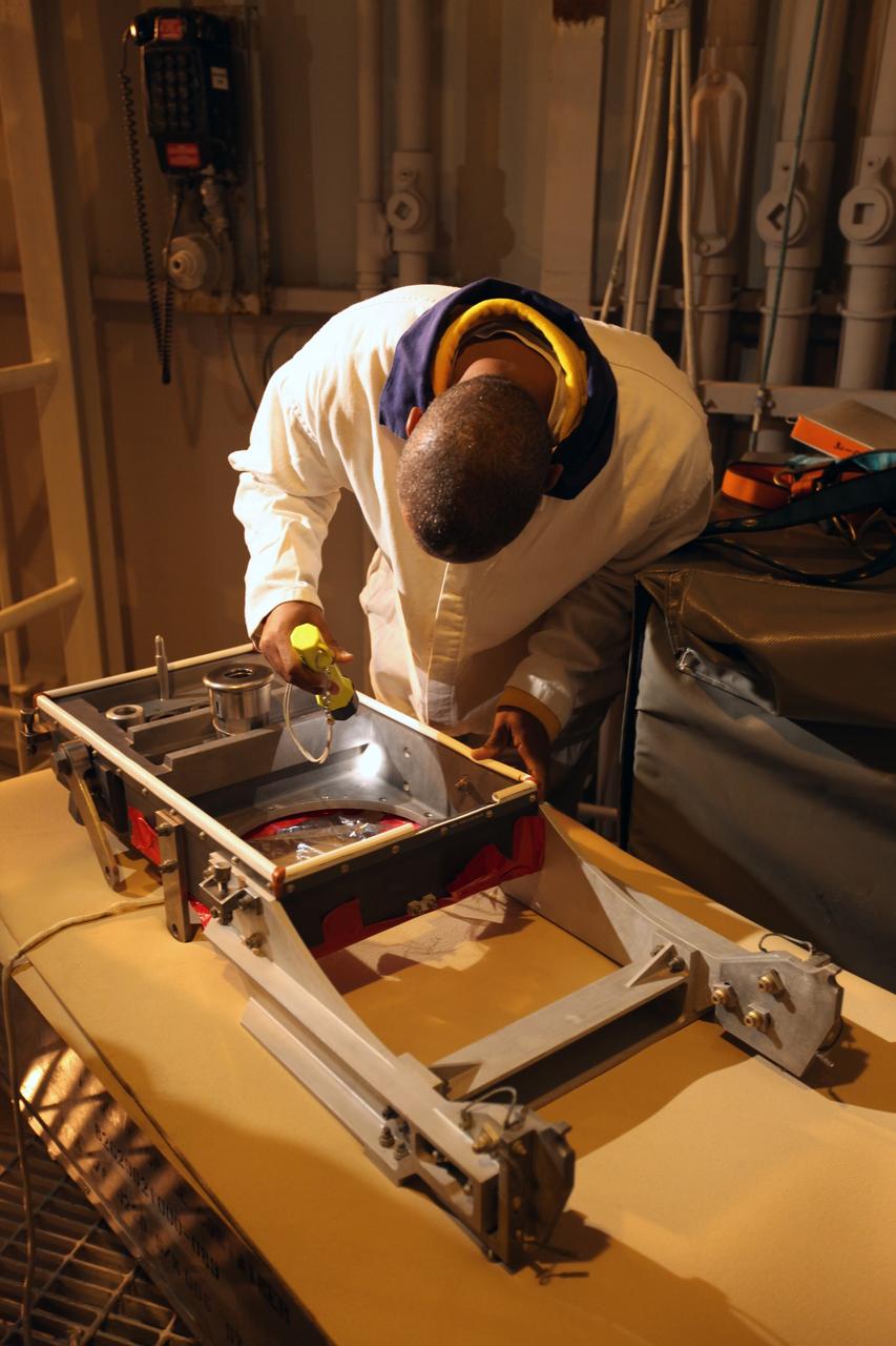 CAPE CANAVERAL, Fla. -- On Launch Pad 39A at NASA's Kennedy Space Center in Florida, workers examine the ground umbilical carrier plate (GUCP). A hydrogen gas leak at that location on the external fuel tank during tanking for space shuttle Discovery's STS-133 mission to the International Space Station caused the launch attempt to be scrubbed Nov. 5. The GUCP will be examined to determine the cause of the hydrogen leak and then repaired. The GUCP is the overboard vent to the pad and the flame stack where the excess hydrogen is burned off.     For more information on STS-133, visit www.nasa.gov/mission_pages/shuttle/shuttlemissions/sts133/. Photo credit: NASA/Dimitri Gerondidakis