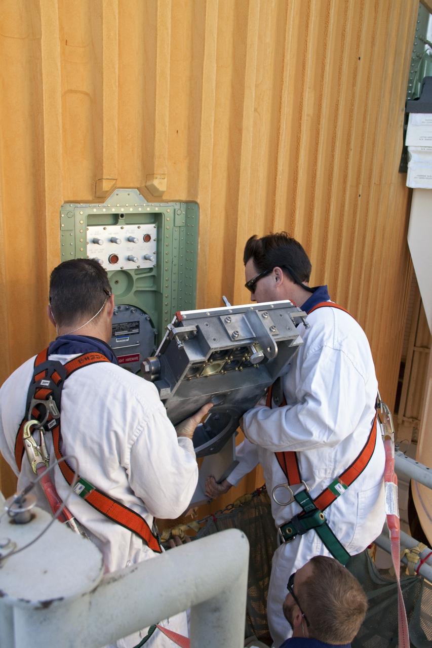 CAPE CANAVERAL, Fla. -- On Launch Pad 39A at NASA's Kennedy Space Center in Florida, workers begin to install a new ground umbilical carrier plate (GUCP) on space shuttle Discovery's external fuel tank. A hydrogen gas leak at that location during tanking for Discovery's STS-133 mission to the International Space Station caused the launch attempt to be scrubbed Nov. 5. The GUCP is the overboard vent to the pad and the flame stack where the excess hydrogen is burned off. For more information on STS-133, visit www.nasa.gov/mission_pages/shuttle/shuttlemissions/sts133/. Photo credit: NASA/Troy Cryder