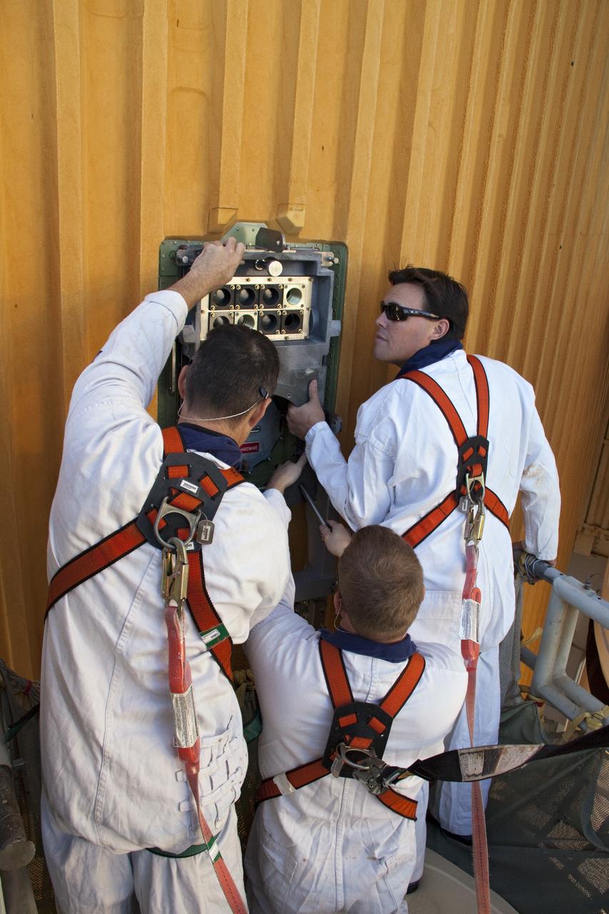 CAPE CANAVERAL, Fla. -- On Launch Pad 39A at NASA's Kennedy Space Center in Florida, workers begin to install a new ground umbilical carrier plate (GUCP) on space shuttle Discovery's external fuel tank. A hydrogen gas leak at that location during tanking for Discovery's STS-133 mission to the International Space Station caused the launch attempt to be scrubbed Nov. 5. The GUCP is the overboard vent to the pad and the flame stack where the excess hydrogen is burned off.       For more information on STS-133, visit www.nasa.gov/mission_pages/shuttle/shuttlemissions/sts133/. Photo credit: NASA/Troy Cryder