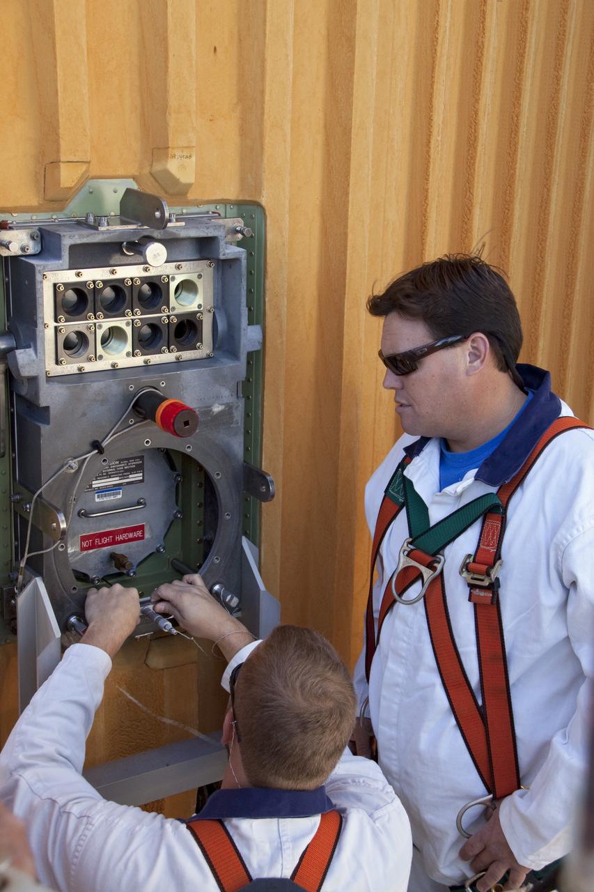 CAPE CANAVERAL, Fla. -- On Launch Pad 39A at NASA's Kennedy Space Center in Florida, workers begin to install a new ground umbilical carrier plate (GUCP) on space shuttle Discovery's external fuel tank. A hydrogen gas leak at that location during tanking for Discovery's STS-133 mission to the International Space Station caused the launch attempt to be scrubbed Nov. 5. The GUCP is the overboard vent to the pad and the flame stack where the excess hydrogen is burned off.         For more information on STS-133, visit www.nasa.gov/mission_pages/shuttle/shuttlemissions/sts133/. Photo credit: NASA/Troy Cryder