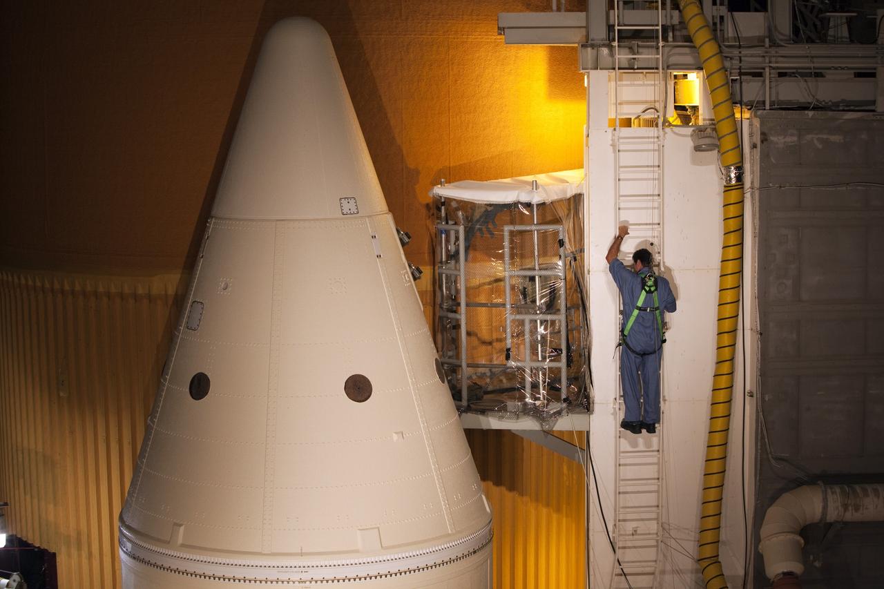 CAPE CANAVERAL, Fla. -- On Launch Pad 39A at NASA's Kennedy Space Center in Florida, a technician climbs toward an environmental enclosure on space shuttle Discovery's external fuel tank. The enclosure will provide protection from wind, temperature and humidity changes while foam is re-applied and cured on the tank. The foam cracked during initial loading operations for Discovery’s launch attempt on Nov. 5. The cracks are on one of the 108 stringers, which are the composite aluminum ribs located vertically on the intertank area.         Discovery's next launch attempt is no earlier than Nov. 30 at 4:02 a.m. EST. For more information on STS-133, visit www.nasa.gov/mission_pages/shuttle/shuttlemissions/sts133/. Photo credit: NASA/Dimitri Gerondidakis
