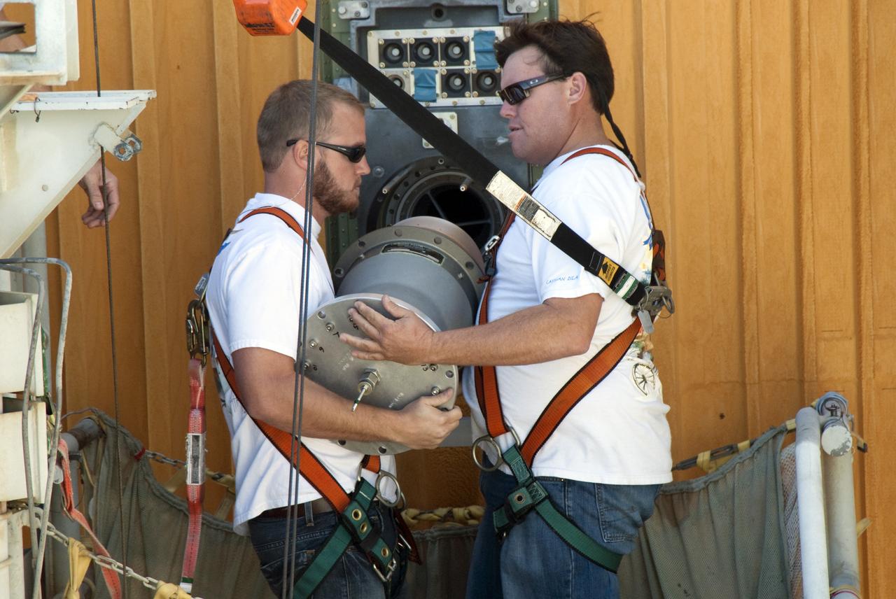 CAPE CANAVERAL, Fla. -- On Launch Pad 39A at NASA's Kennedy Space Center in Florida, workers install a new 7-inch quick disconnect on the ground umbilical carrier plate (GUCP) of space shuttle Discovery's external fuel tank. A hydrogen gas leak at that location during tanking for Discovery's STS-133 mission to the International Space Station caused the launch attempt to be scrubbed Nov. 5. The GUCP is the overboard vent to the pad and the flame stack where the excess hydrogen is burned off.         For more information on STS-133, visit www.nasa.gov/mission_pages/shuttle/shuttlemissions/sts133/. Photo credit: NASA/Charisse Nahser